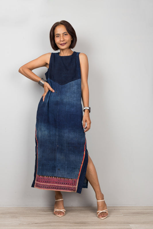 Petite Woman wearing a blue cotton dress with embroidery, pockets and a slit on a plain background