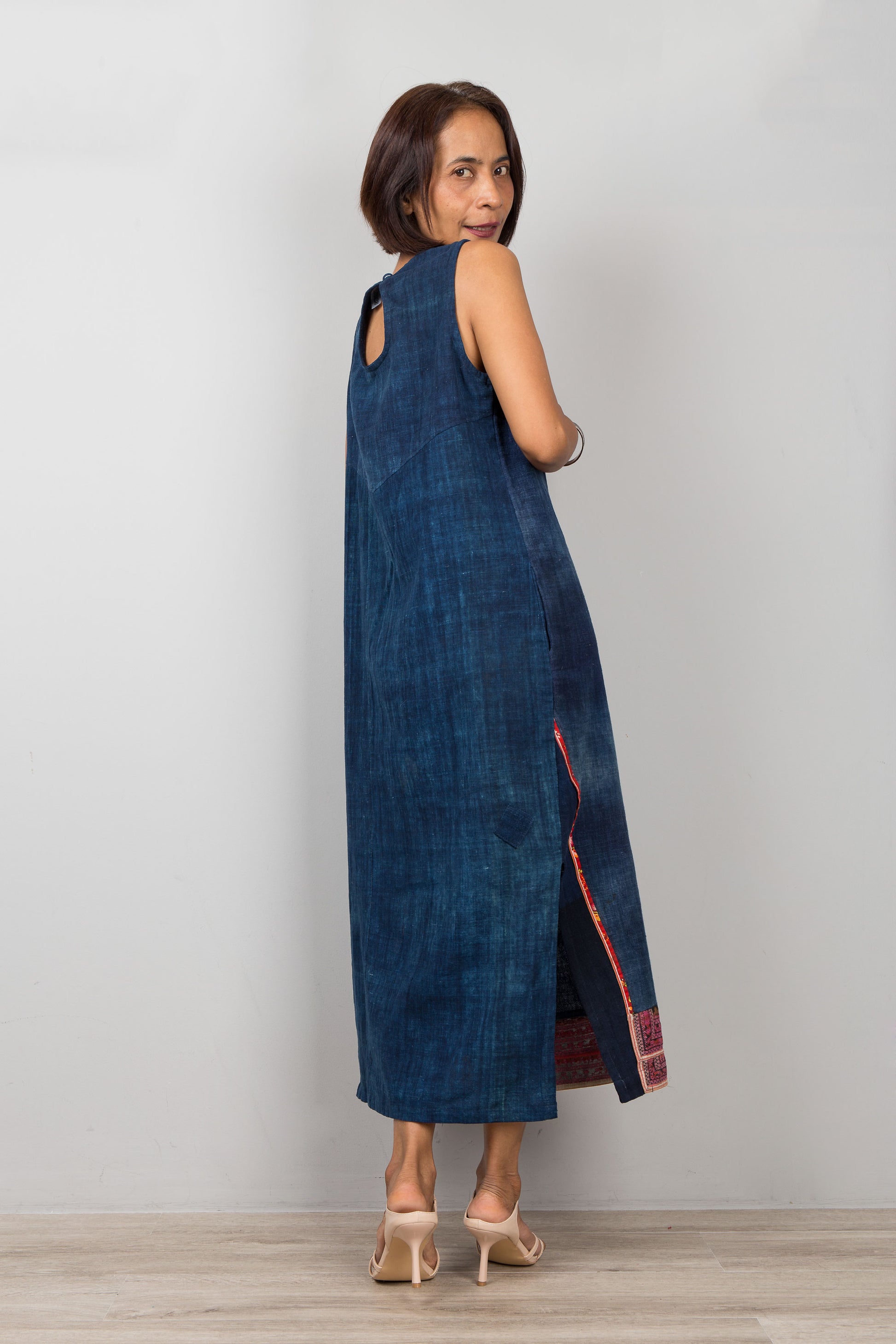 Petite Woman wearing a blue cotton dress with embroidery and a slit on a plain background