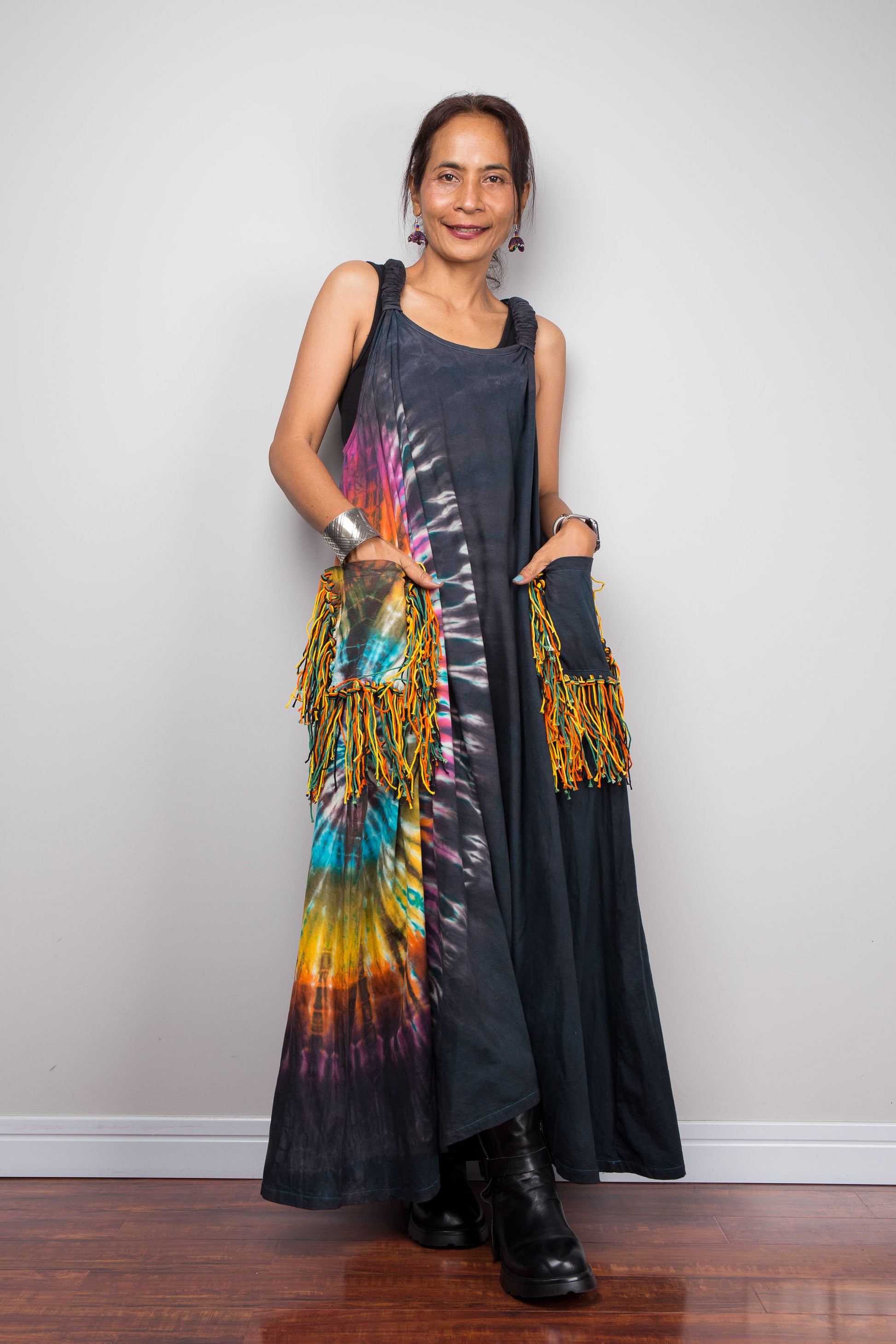 Front view of a model wearing the Nuichan sleeveless tie-dye boho maxi dress, showing the scoop neckline, flowing A-line silhouette, and multicolour yarn fringe patch pockets on both hips.