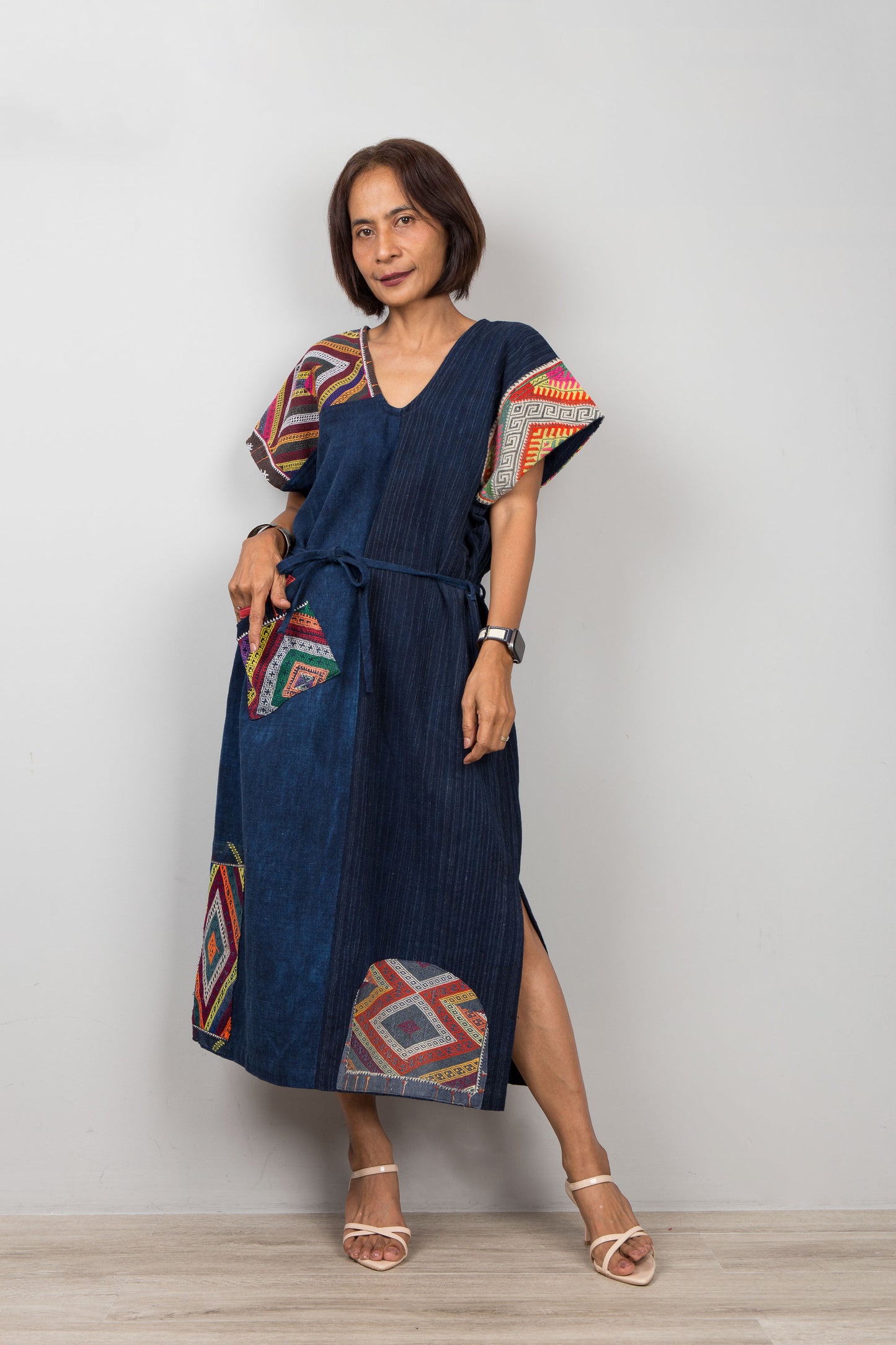 Woman wearing a blue dress with colorful patterns on a white background