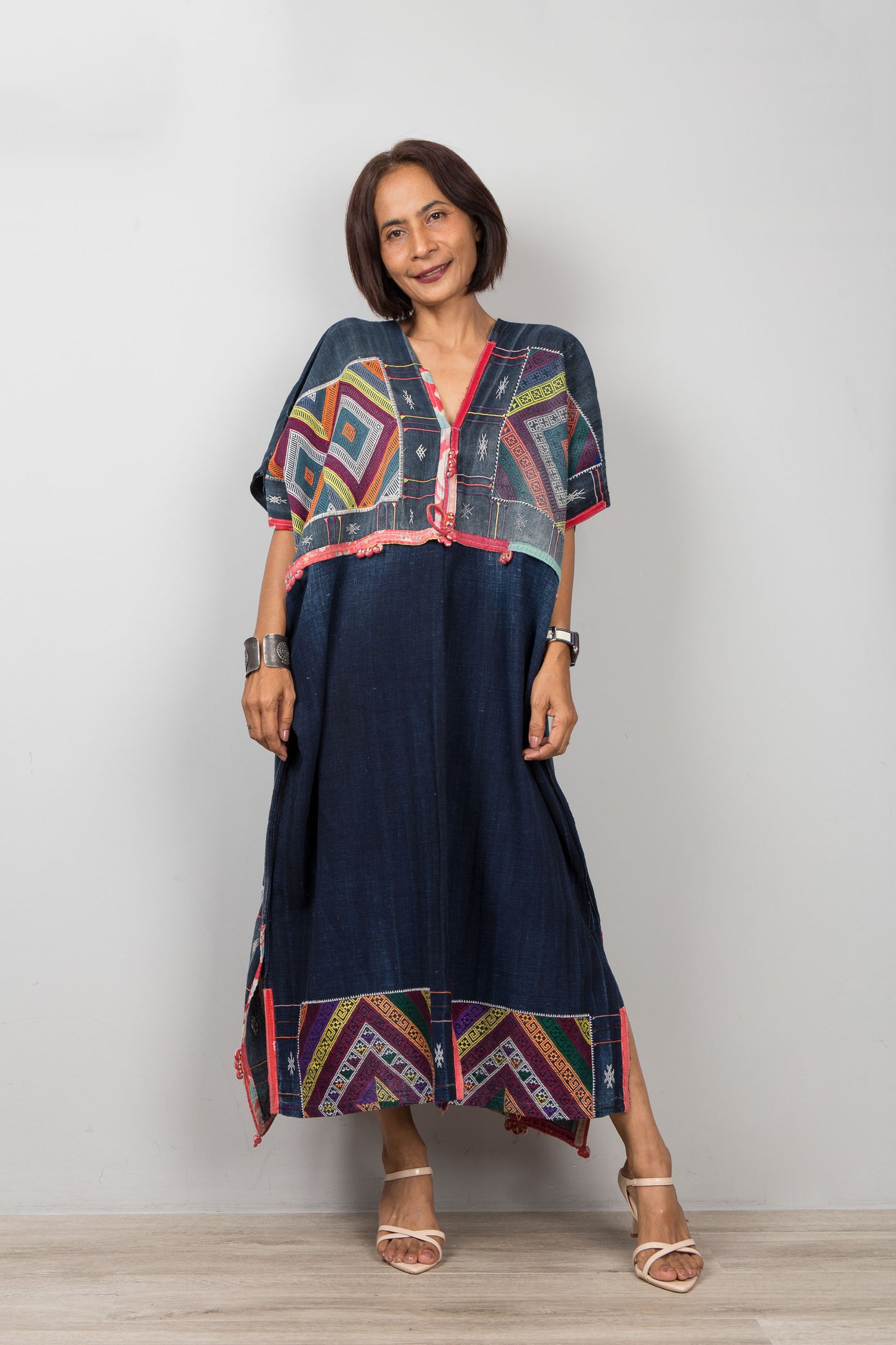 Woman wearing a colorful dress with geometric patterns on a plain background