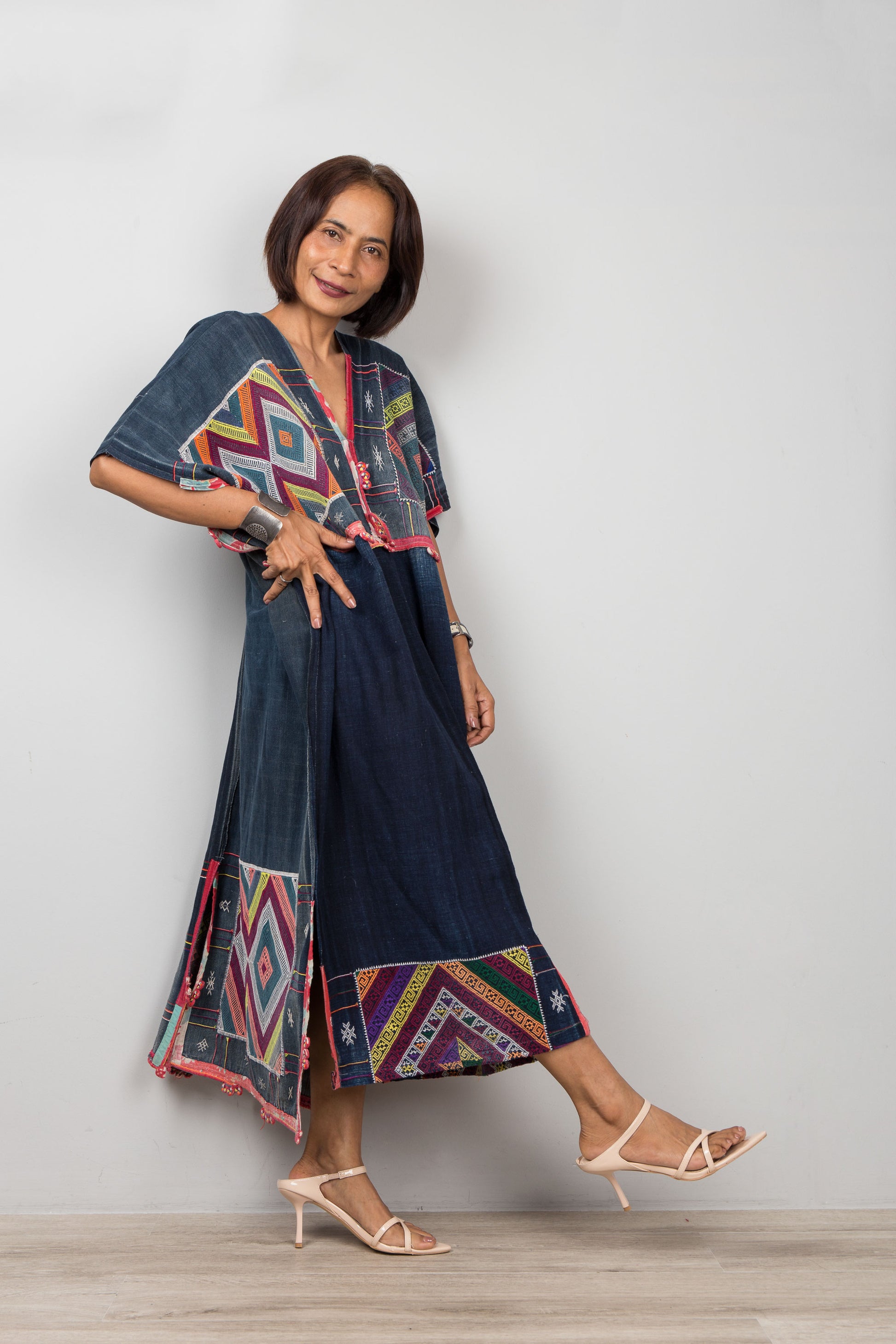 Woman wearing a colorful dress with geometric patterns on a plain background