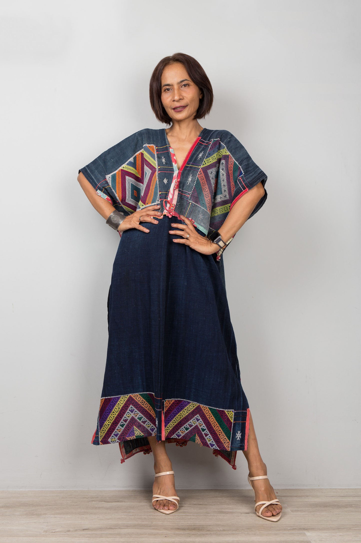 Woman wearing a colorful dress with geometric patterns on a plain background