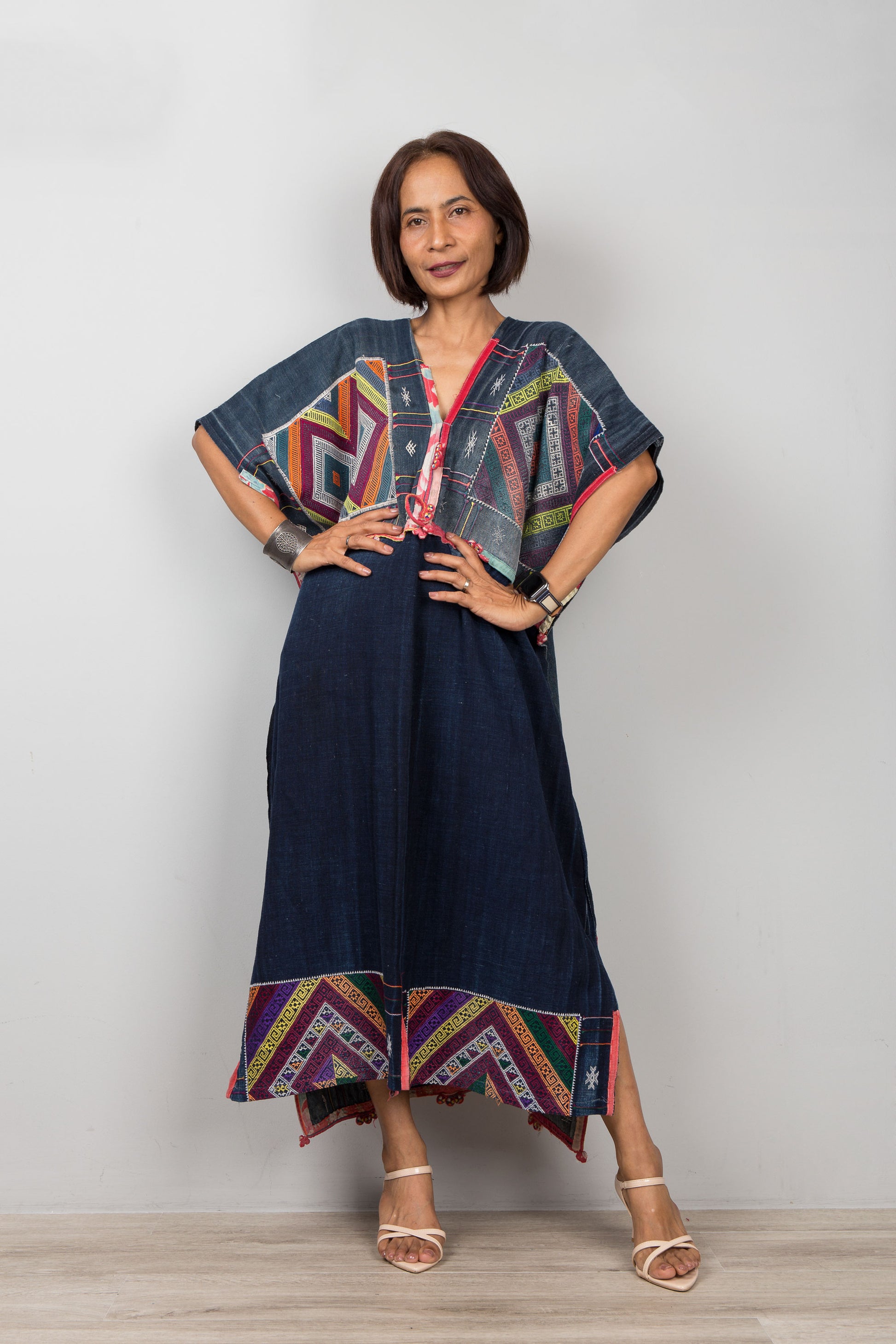 Woman wearing a colorful dress with geometric patterns on a plain background