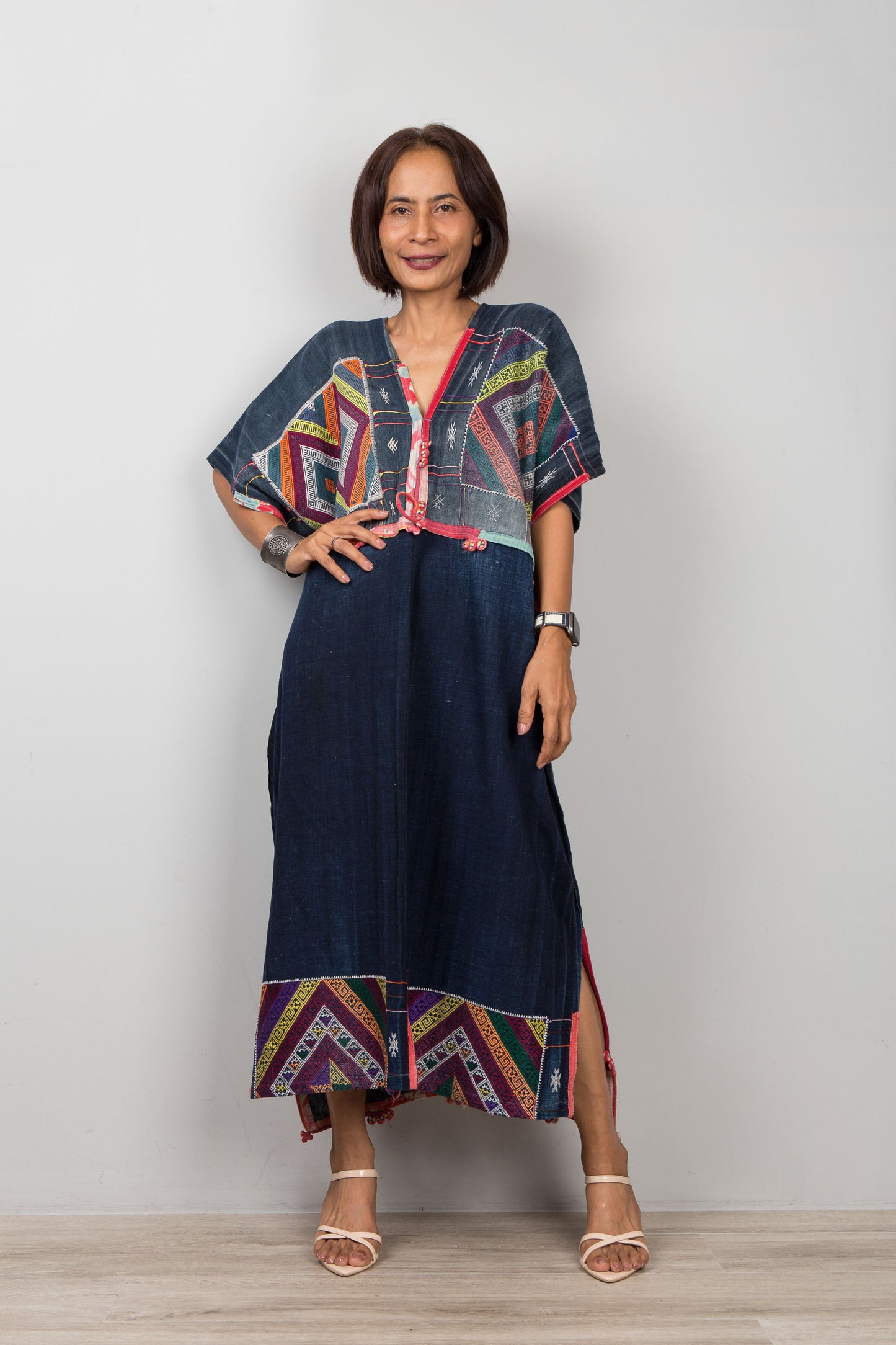Woman wearing a colorful dress with a geometric pattern against a plain background