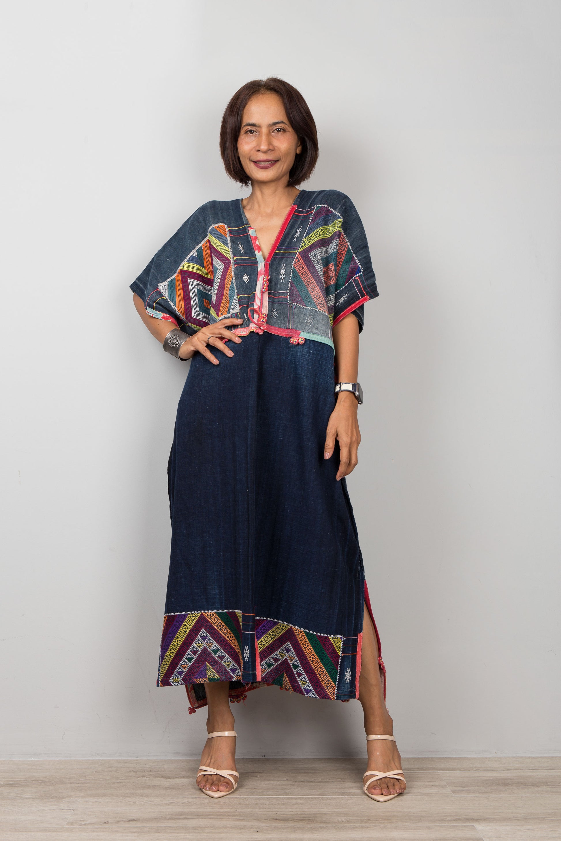 Woman wearing a colorful dress with a geometric pattern against a plain background