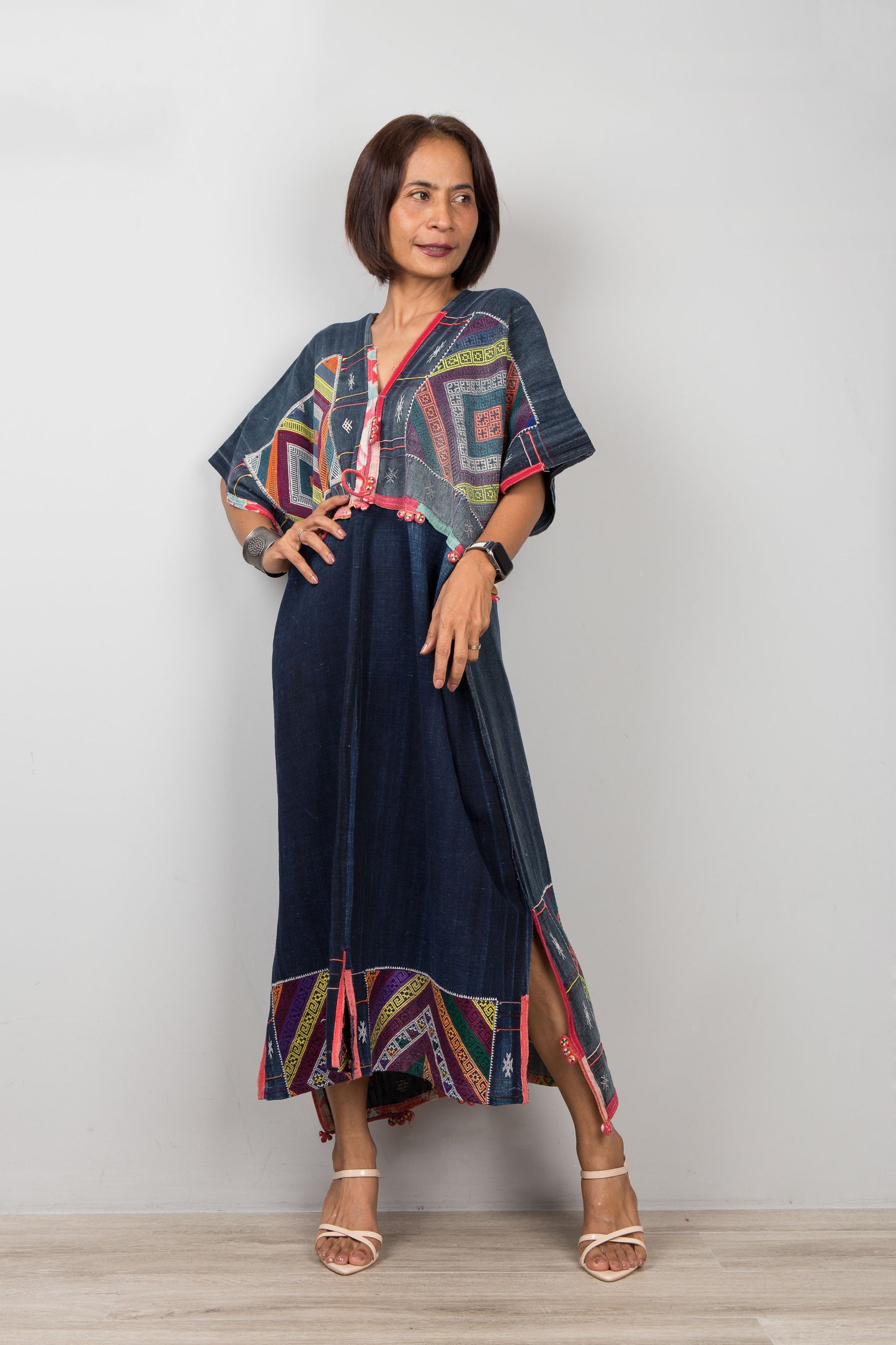 Woman wearing a colorful kimono-style top and navy skirt against a plain background