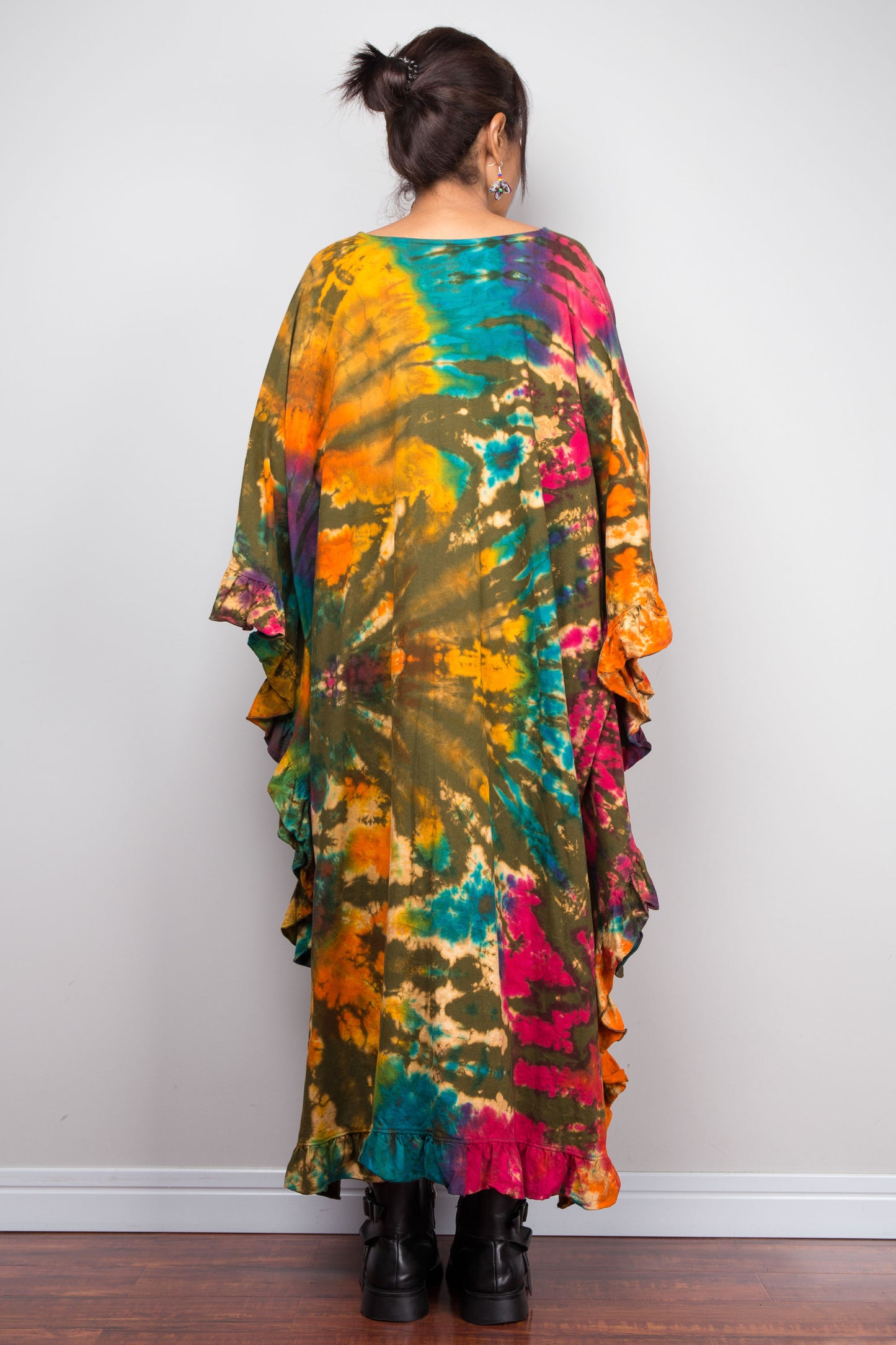 Rear view of a person wearing a colorful tie-dye caftan tunic dress against a plain background