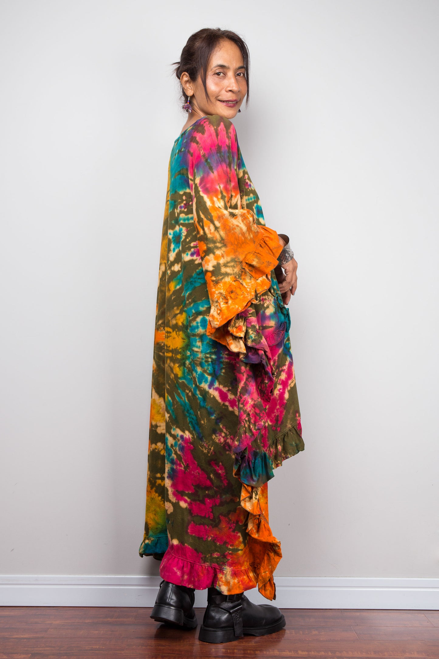 Rear side view of a Person wearing a colorful, long, tie-dye garment against a plain background