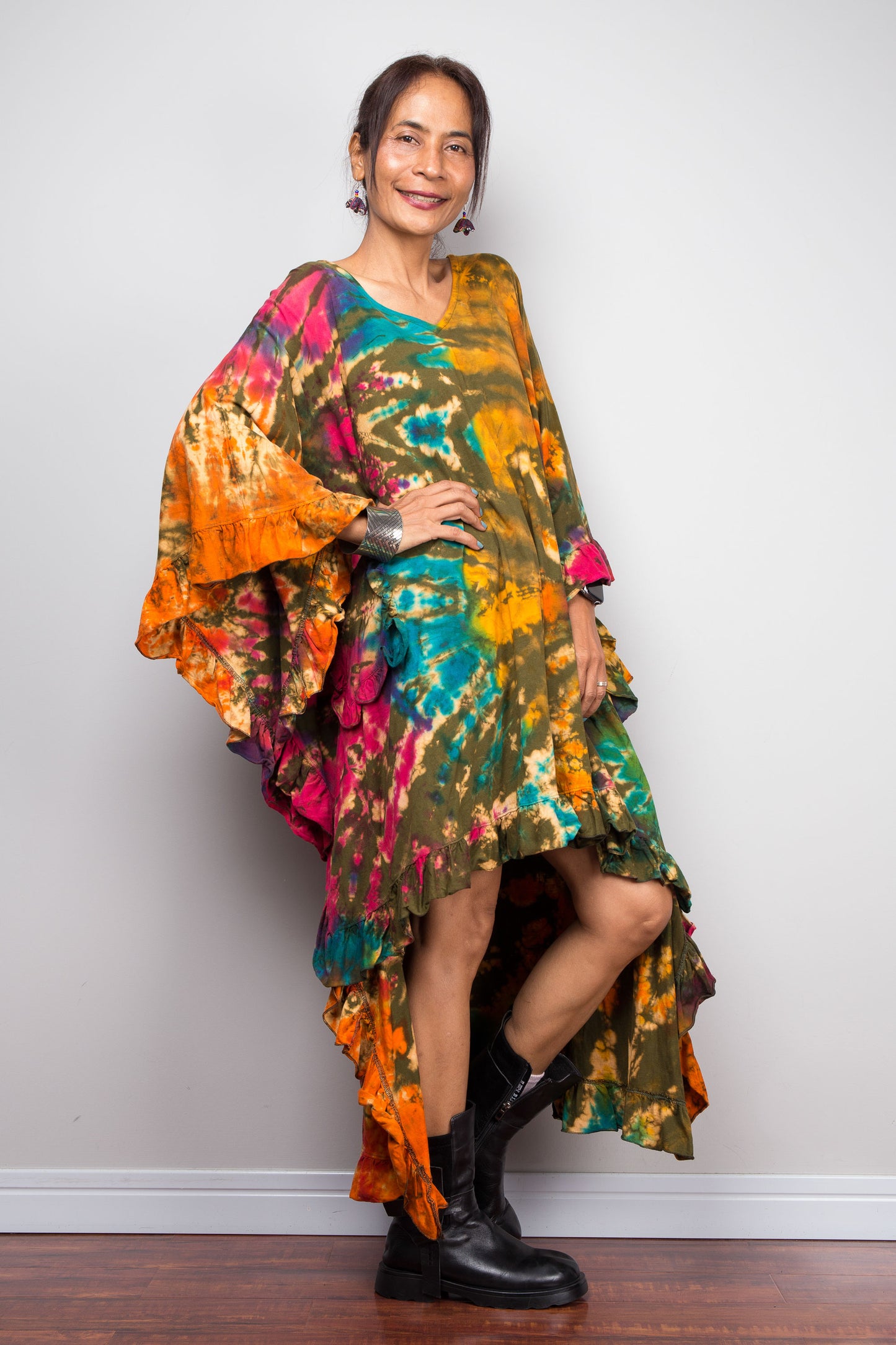 Woman wearing a colorful, patterned tie dye kaftan top dress against a plain background