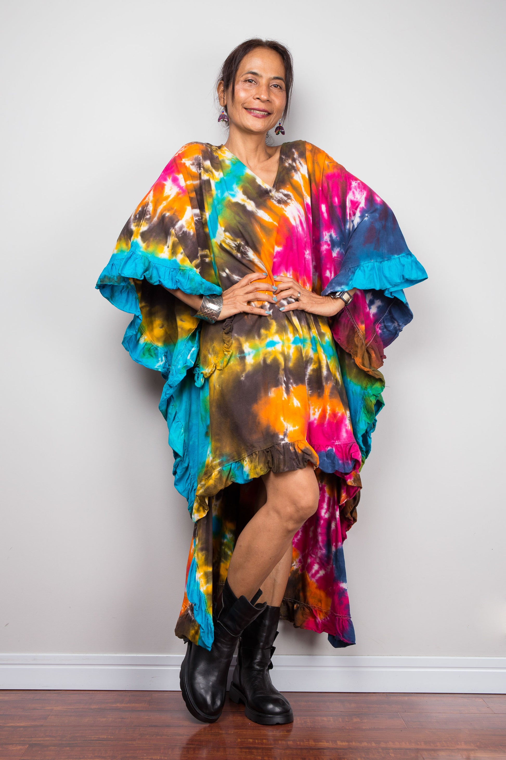 A woman wearing a unique Nuichan vibrant, multicolored tie dye caftan tunic with a high-low hemline that is short in the front and cascades into a long train at the back