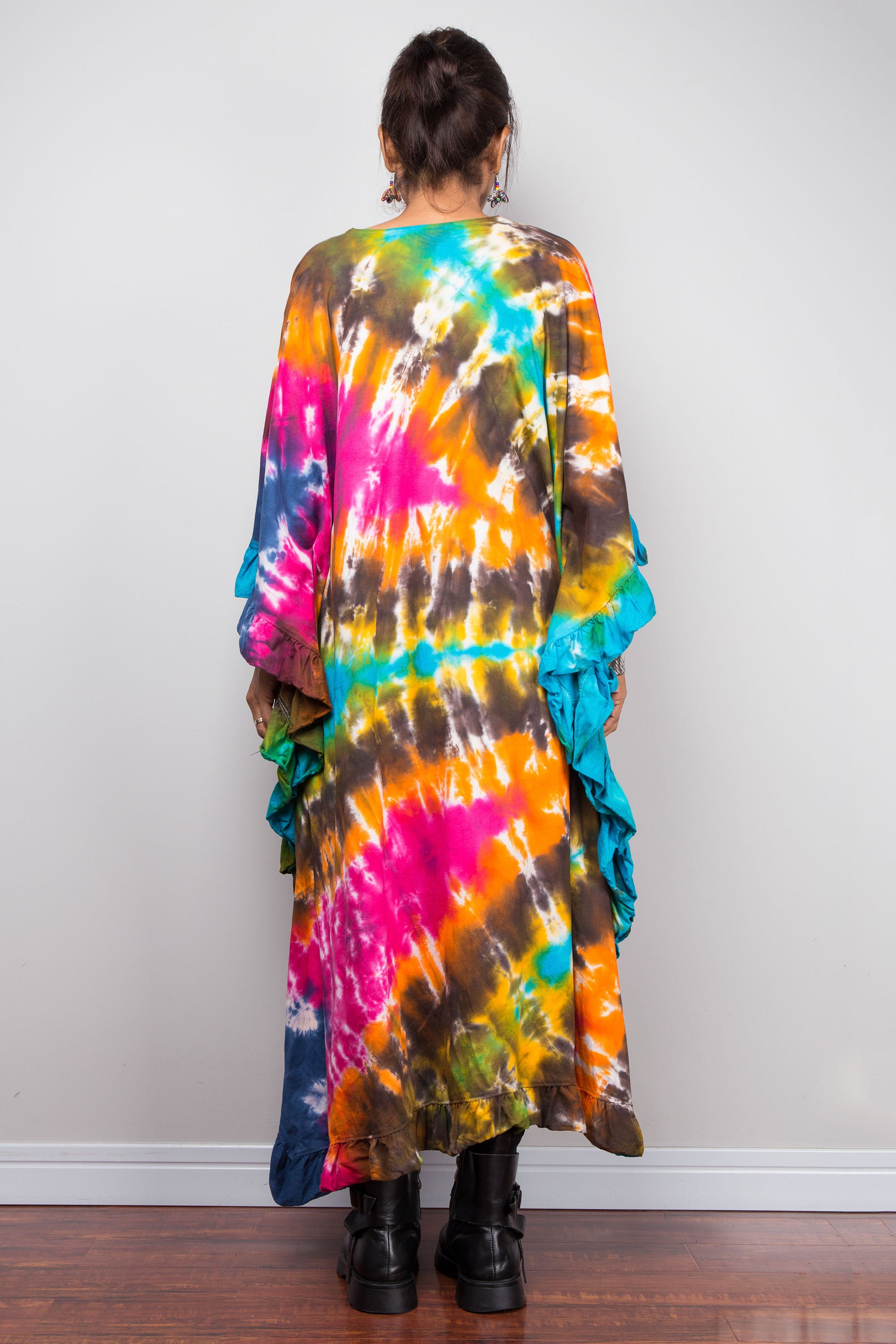 Back view of a woman wearing a unique Nuichan vibrant, multicolored tie-dye kaftan tunic with a high-low hemline that is short in the front and cascades into a long train at the back
