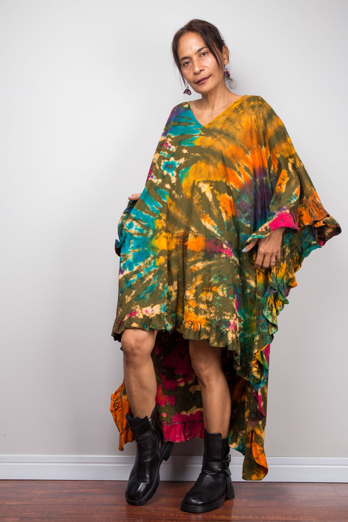 Woman wearing a colorful tie-dye kaftan dress against a plain background