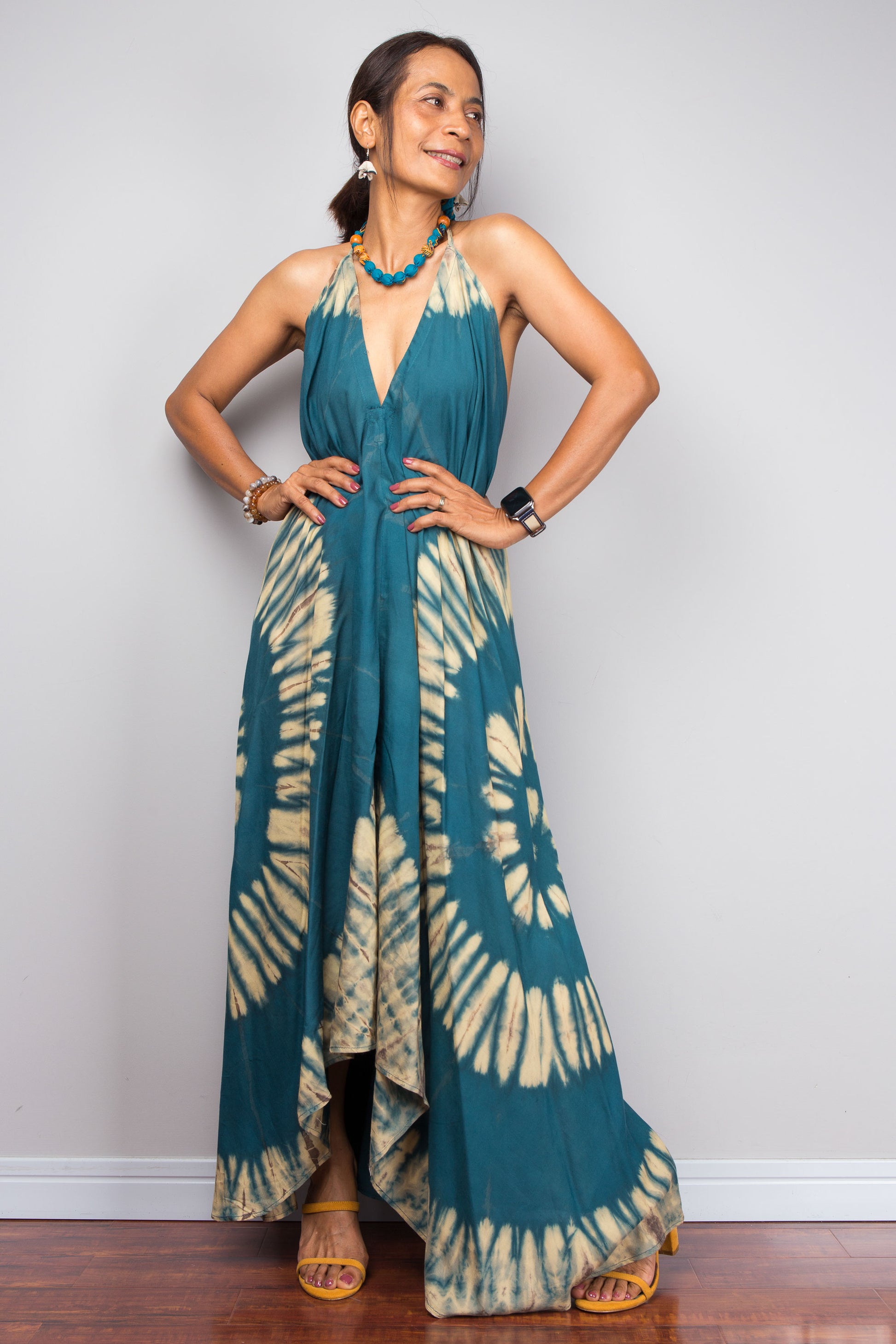 Woman wearing a teal and beige tie-dye dress against a plain background