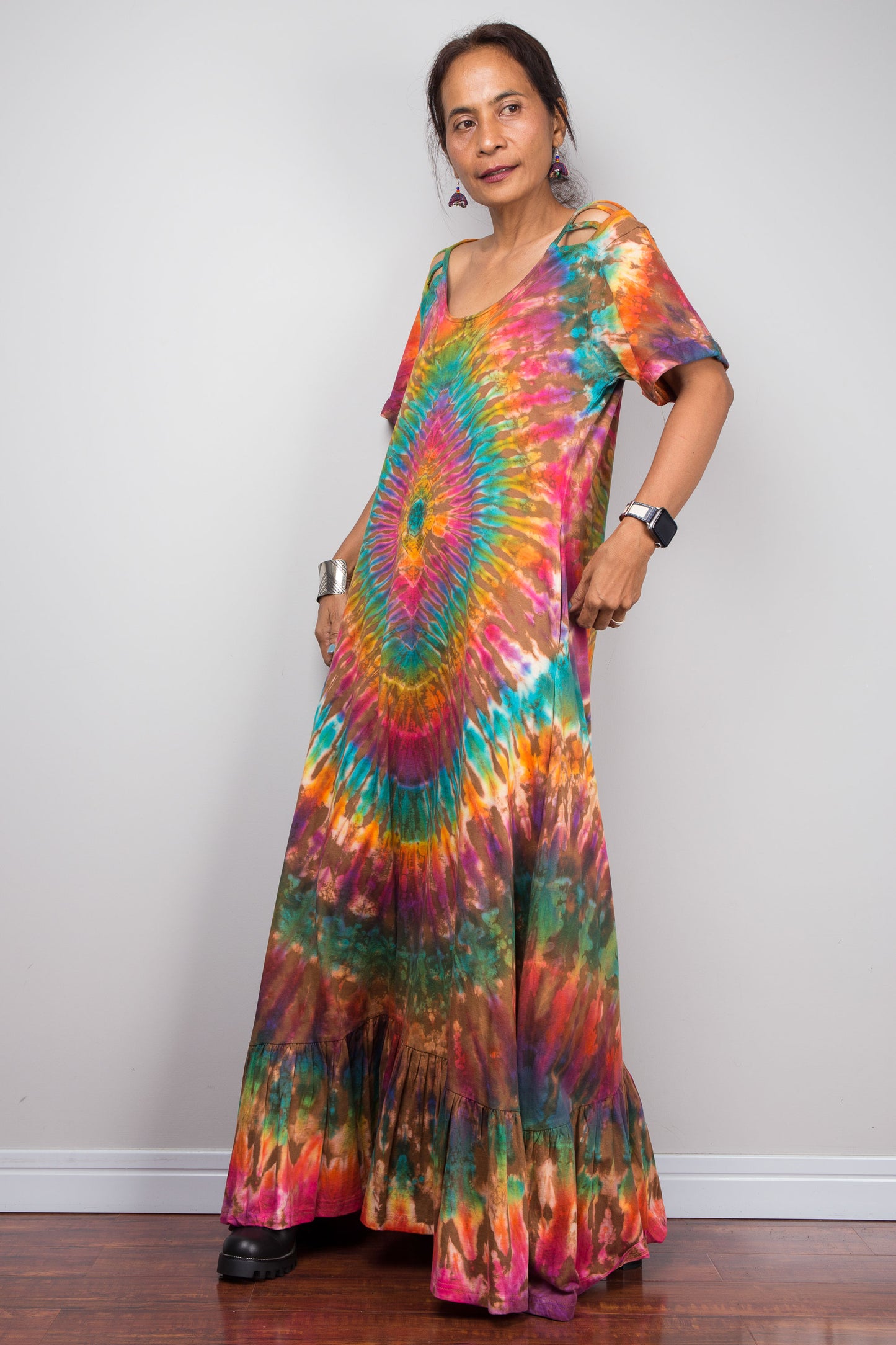 Woman wearing a tie-dye dress with a colorful spiral pattern against a plain background