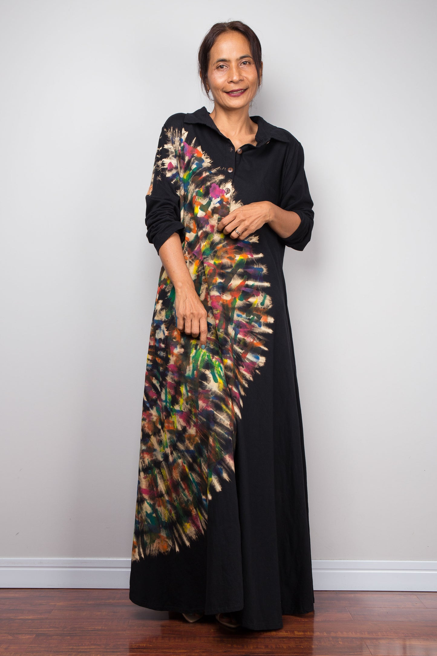 Woman wearing a black tie dye dress with a colorful, pattern against a white background