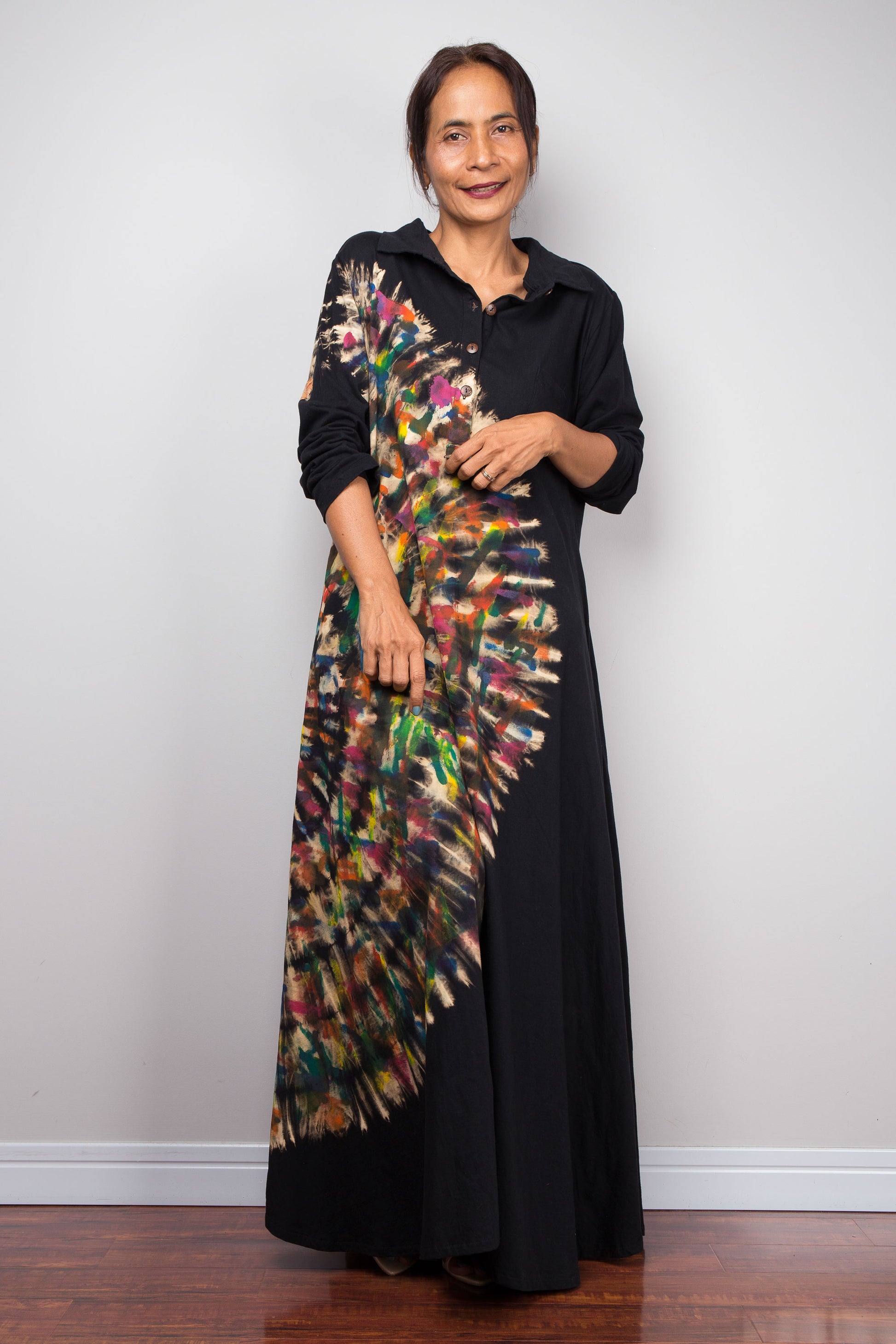 Woman wearing a black tie dye dress with a colorful, pattern against a white background