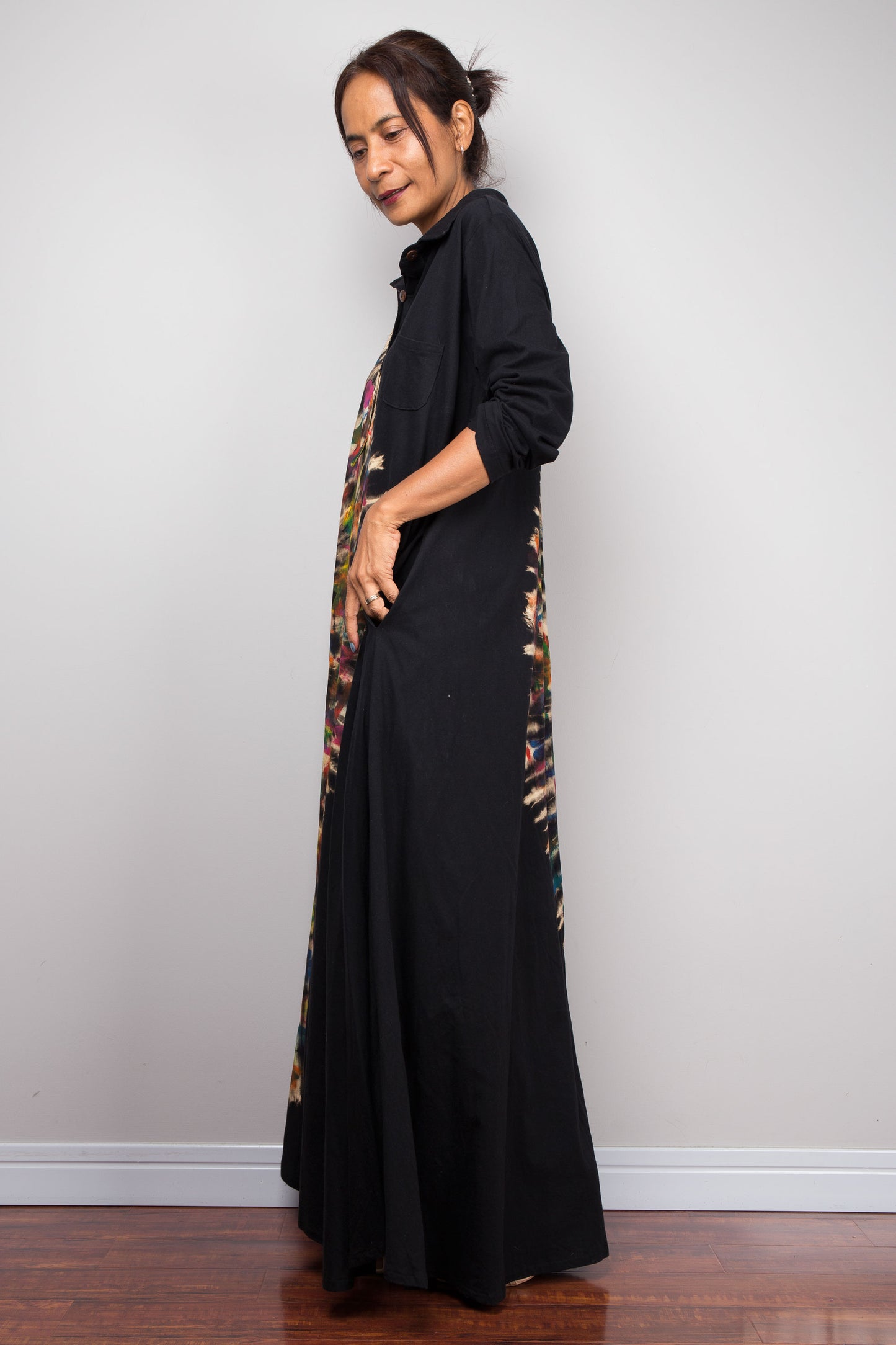 Woman wearing a long black dress with a patterned side panel against a plain background