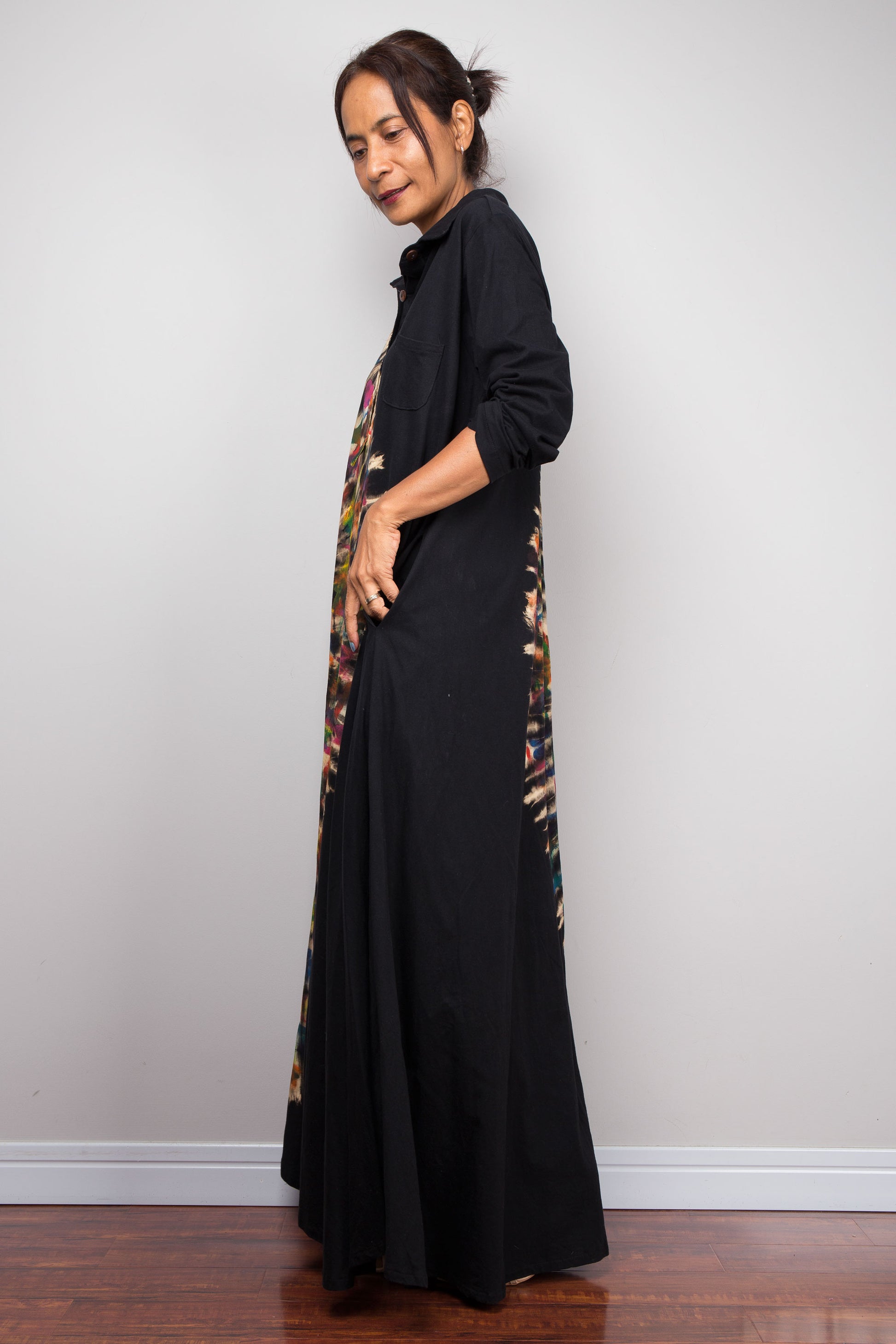 Woman wearing a long black dress with a patterned side panel against a plain background