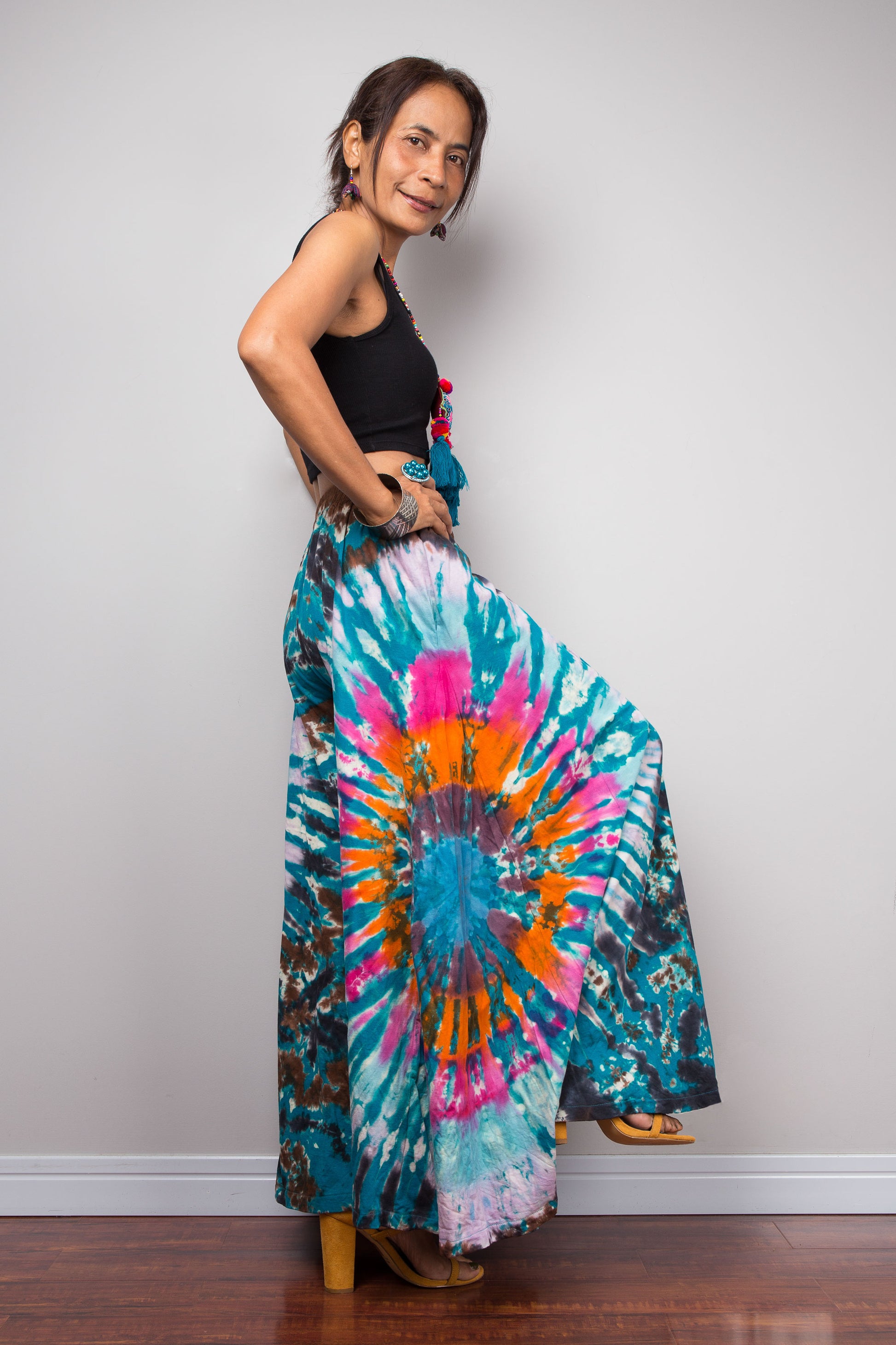 Side profile view of a model wearing the Nuichan multicolour tie dye palazzo pants, displaying the fluid side drape of the ultra-wide cotton leg, hidden side pocket placement, and the layered depth of the multicolour freeform starburst tie dye pattern