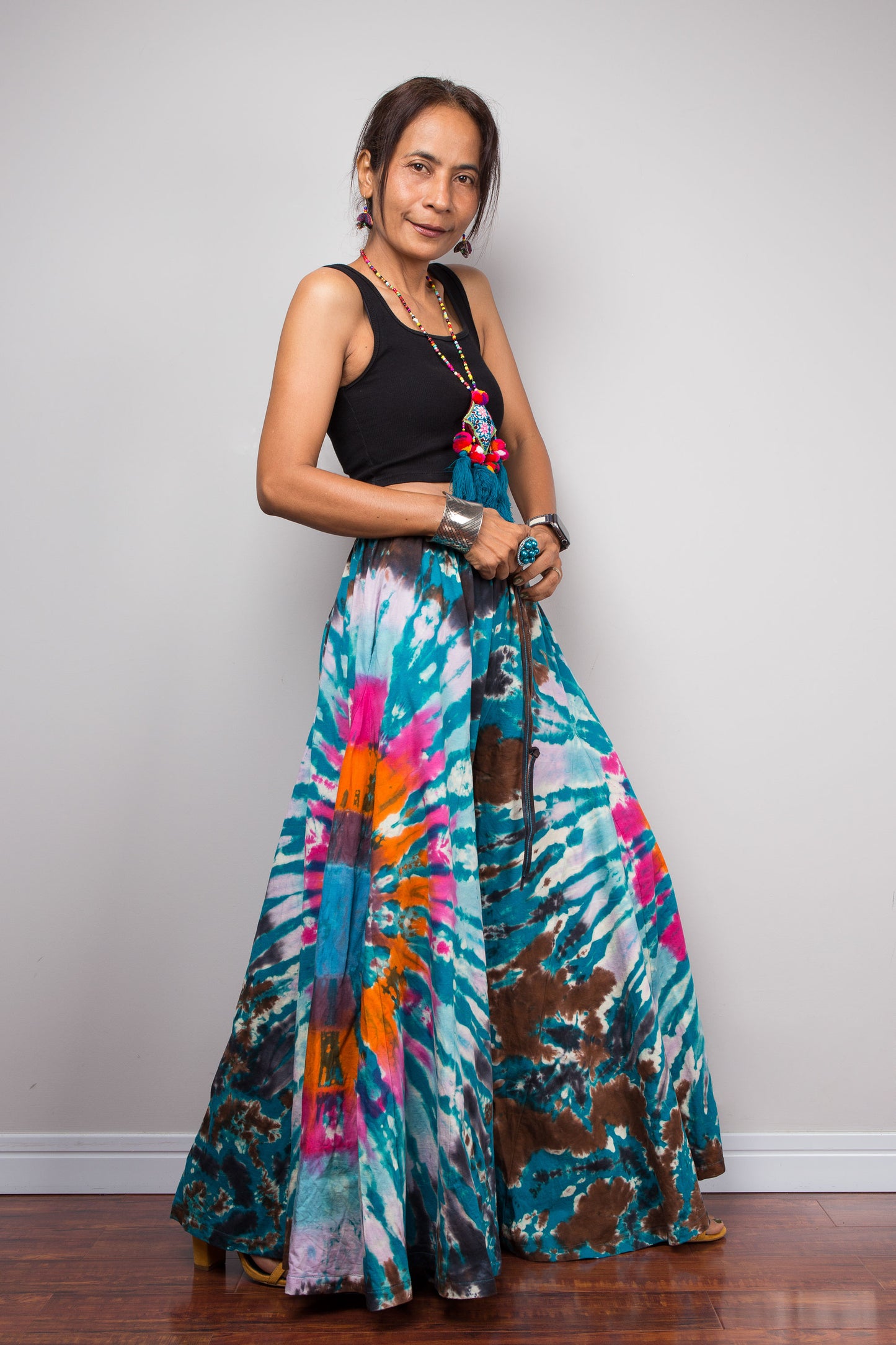 Full-length side view of a petite model in the Nuichan multicolour tie dye wide leg palazzo pants, illustrating how the unstructured ultra-wide cotton legs mimic the elegant sweeping flow of a maxi skirt from waist to floor