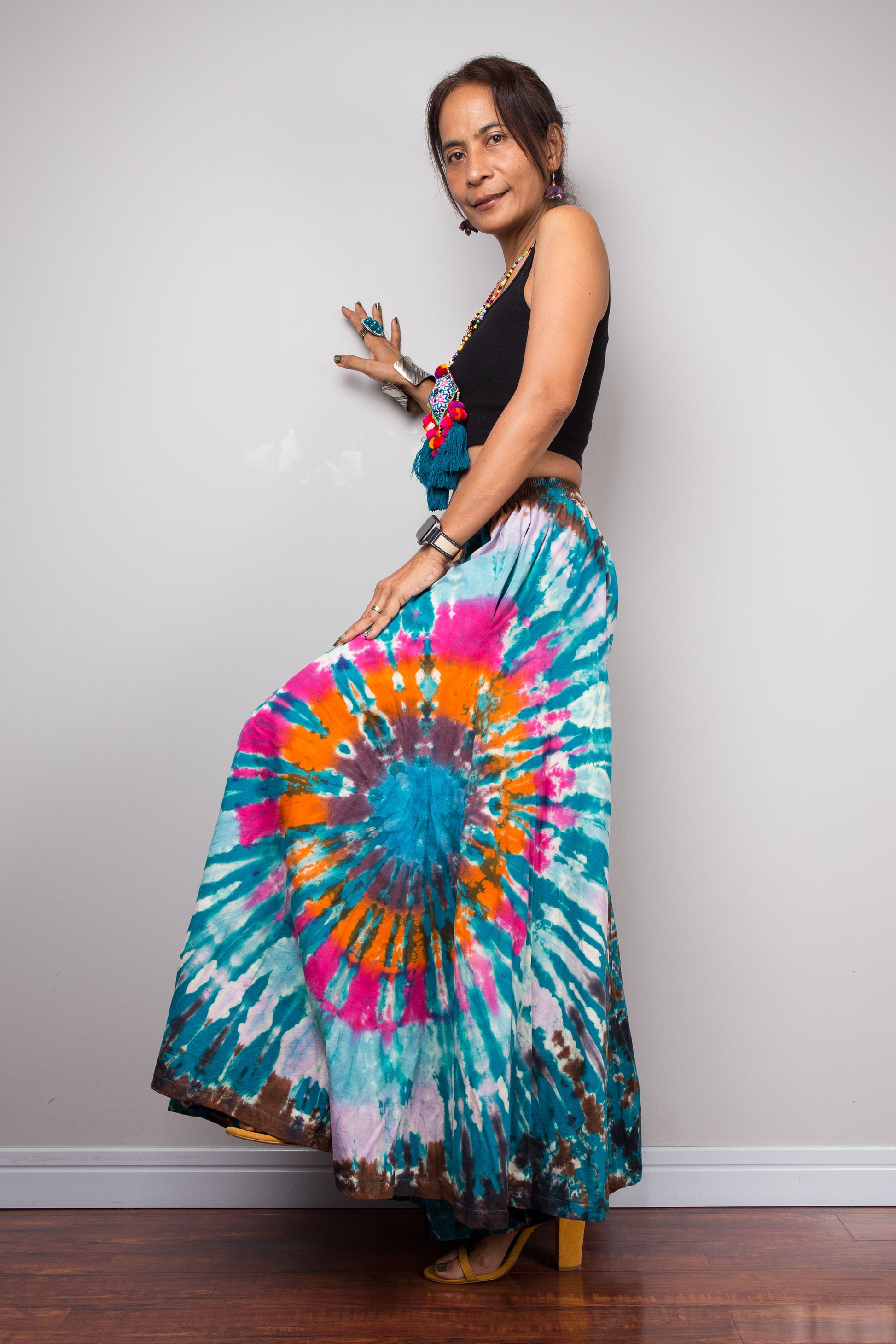 Dynamic pose of a petite model wearing the Nuichan multicolour tie dye palazzo pants, showcasing the immense fabric movement and sweeping A-line drape of the ultra-wide cotton legs as they catch the air, styled with a black crop top
