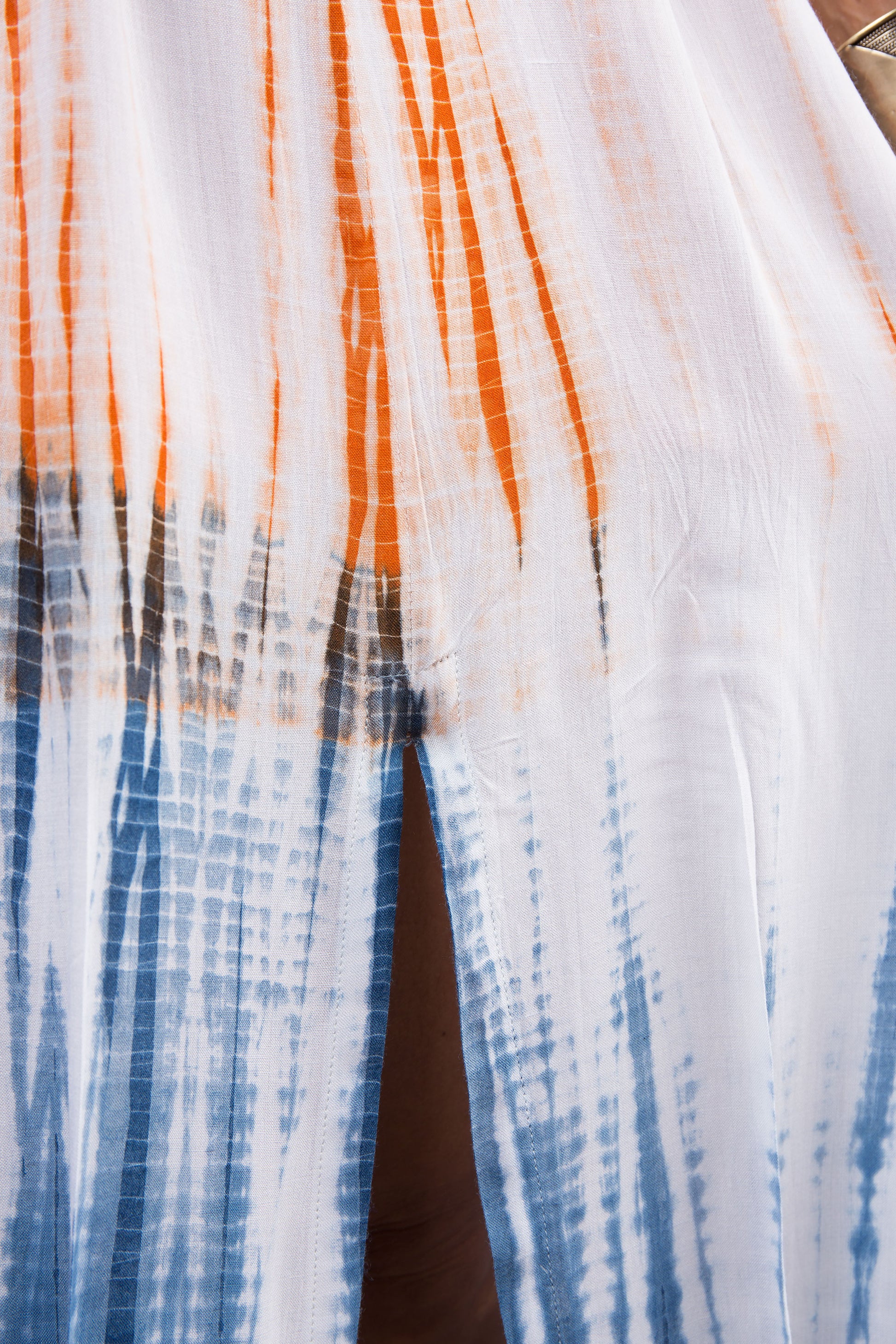 Close-up of the intricate shibori tie dye pattern on the blue and orange cotton dress, highlighting the unique design.