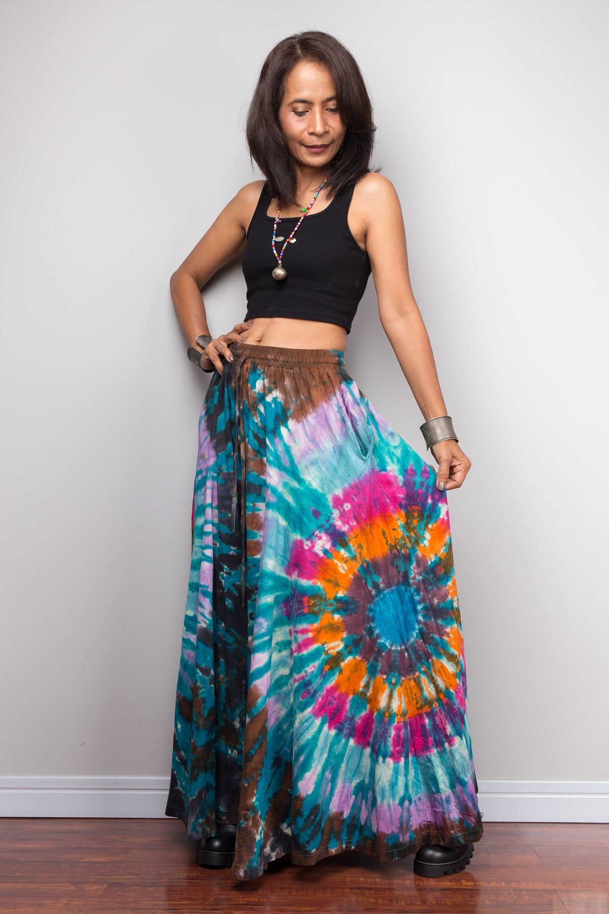 Side profile view of woman wearing teal tie dye palazzo pants, showing the drape and movement of the wide-leg silhouette