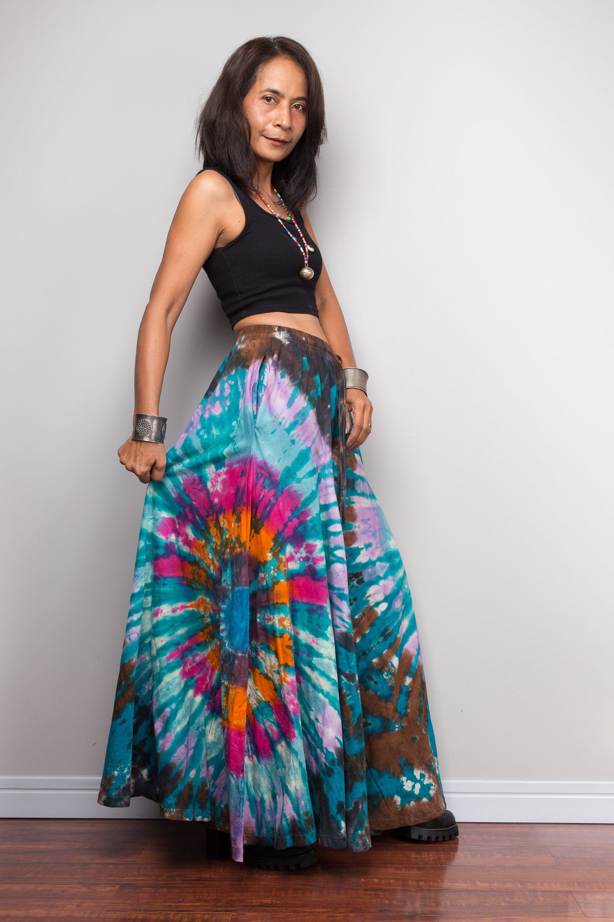 Side profile view of woman wearing teal tie dye palazzo pants by Nuichan, showing the drape and movement of the wide-leg silhouette