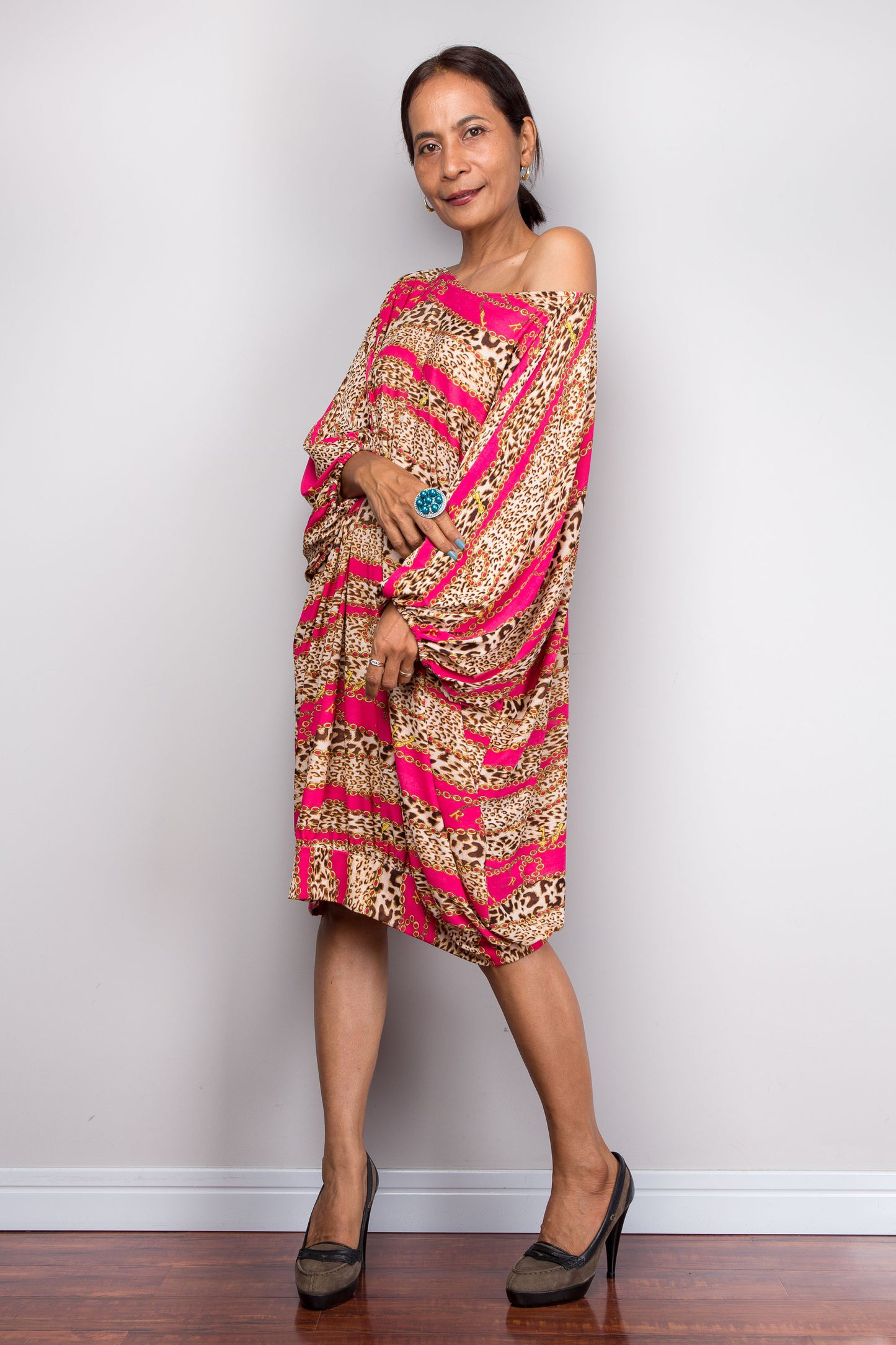 Woman wearing a pink and gold patterned dress against a plain background