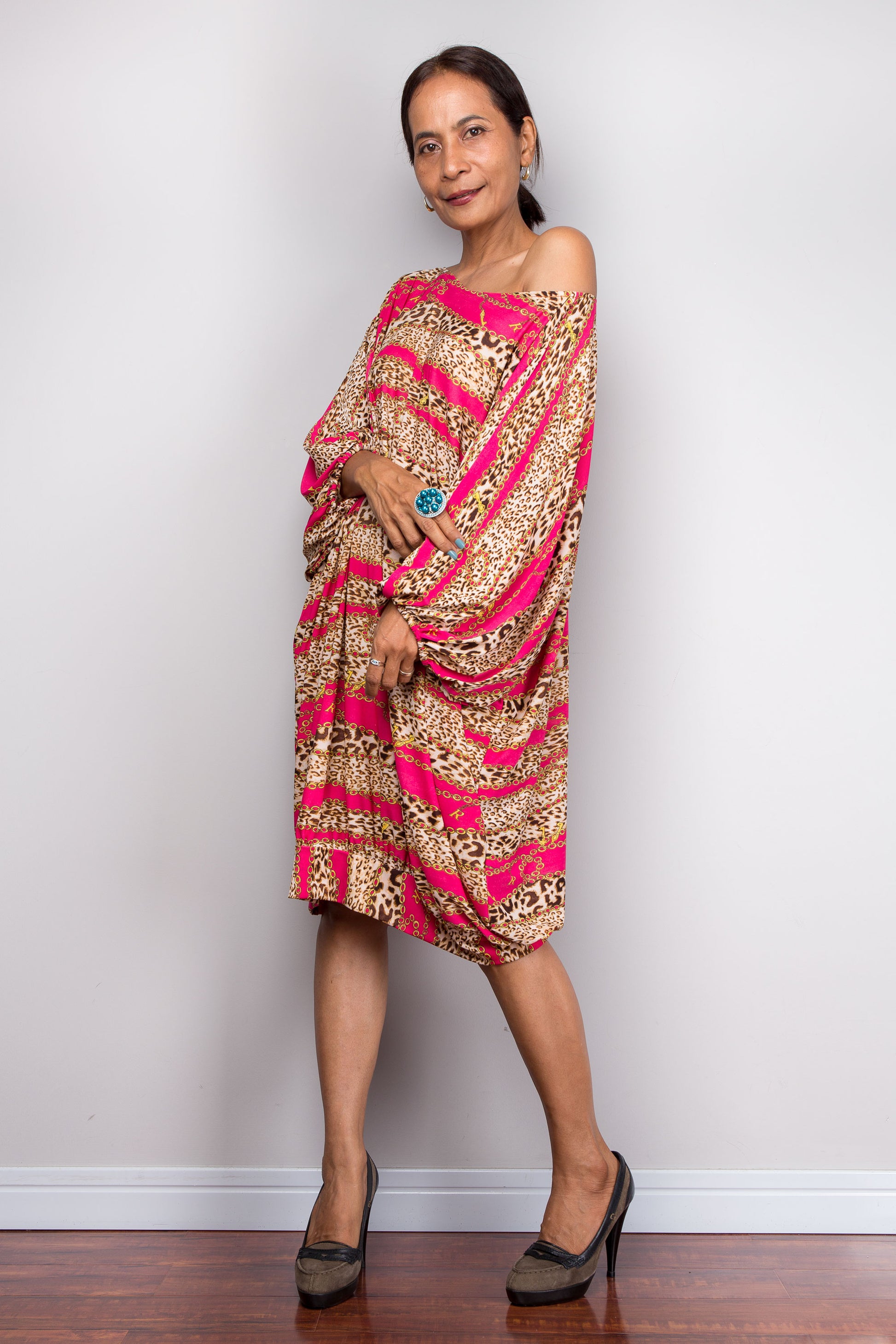 Woman wearing a pink and gold patterned dress against a plain background