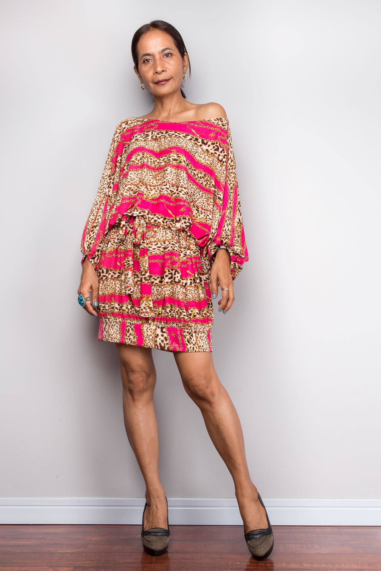 Petite Woman wearing a patterned tunci dress with pink accents against a plain background