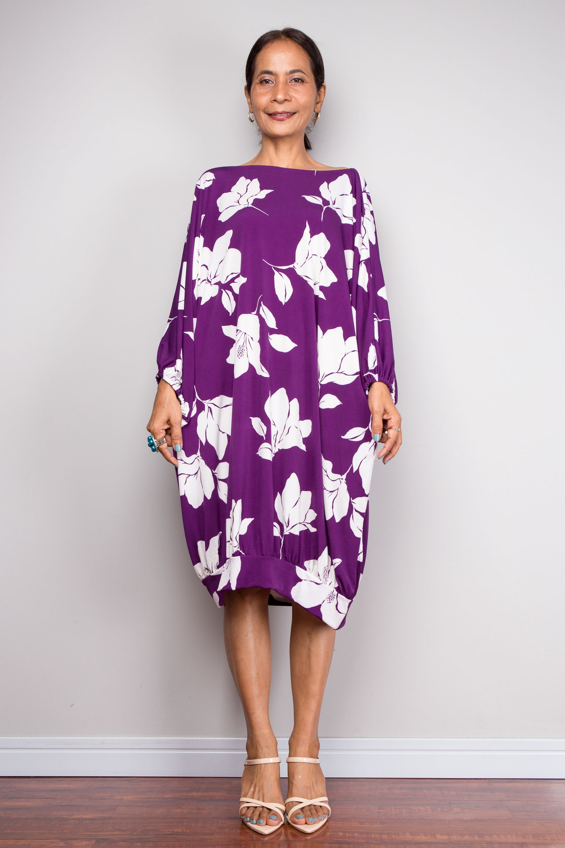 Woman wearing a purple petite kaftan tunic dress with white floral pattern against a plain background