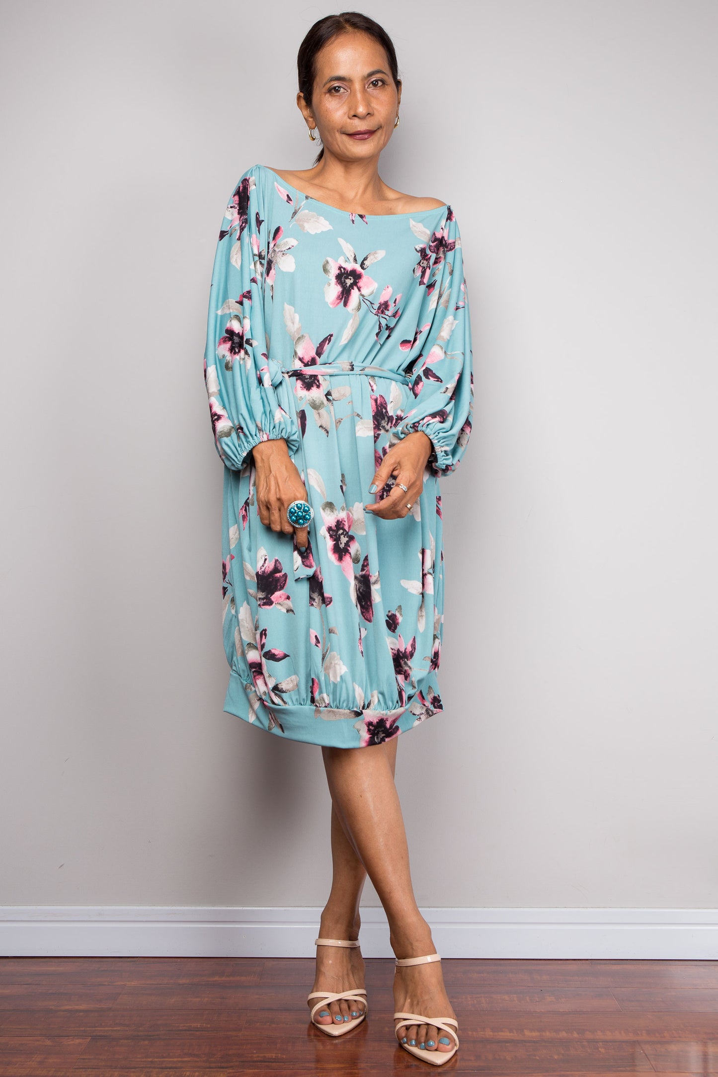 Woman wearing a blue floral dress against a plain background