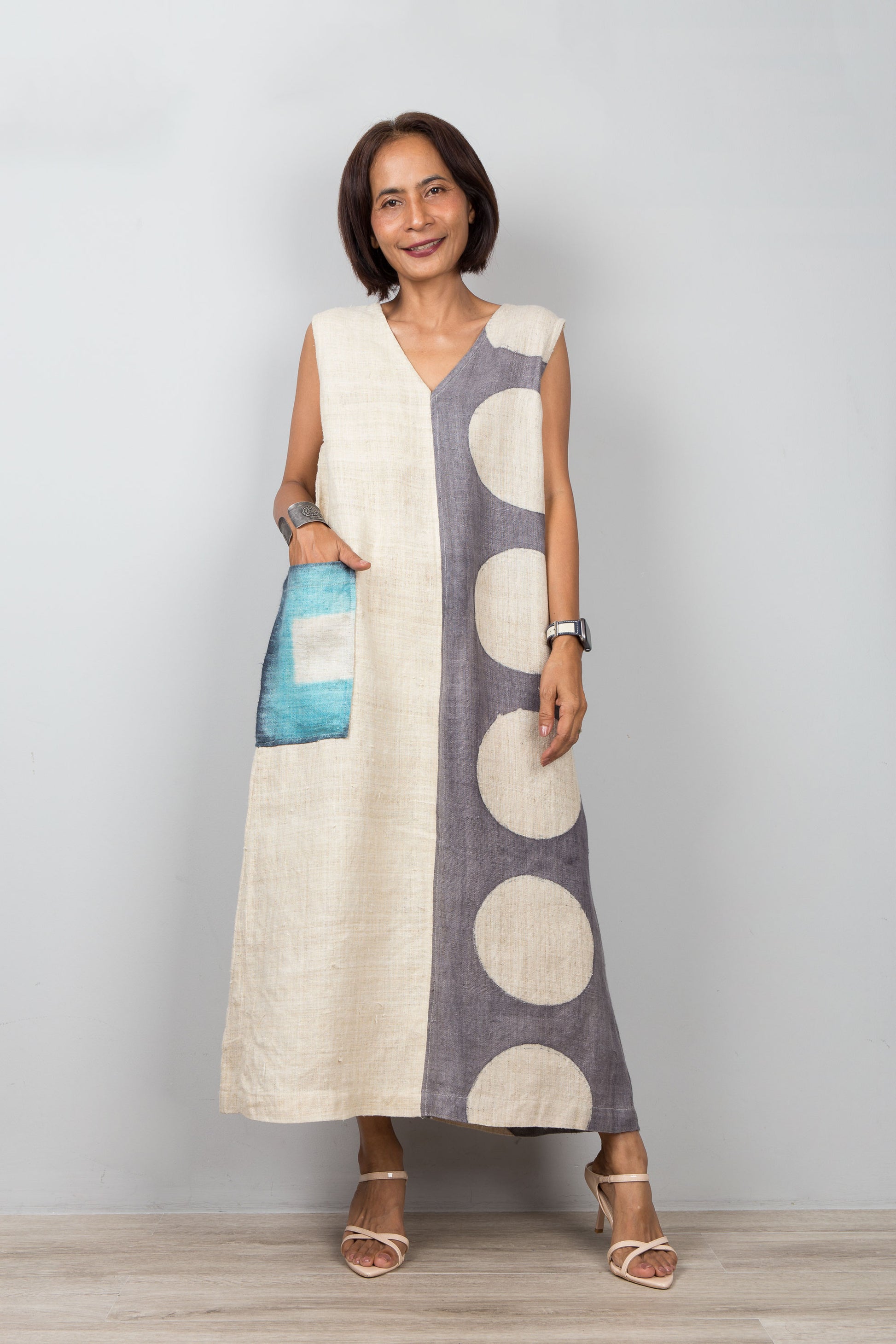 Woman wearing a sleeveless dress with circular patterns on a plain background