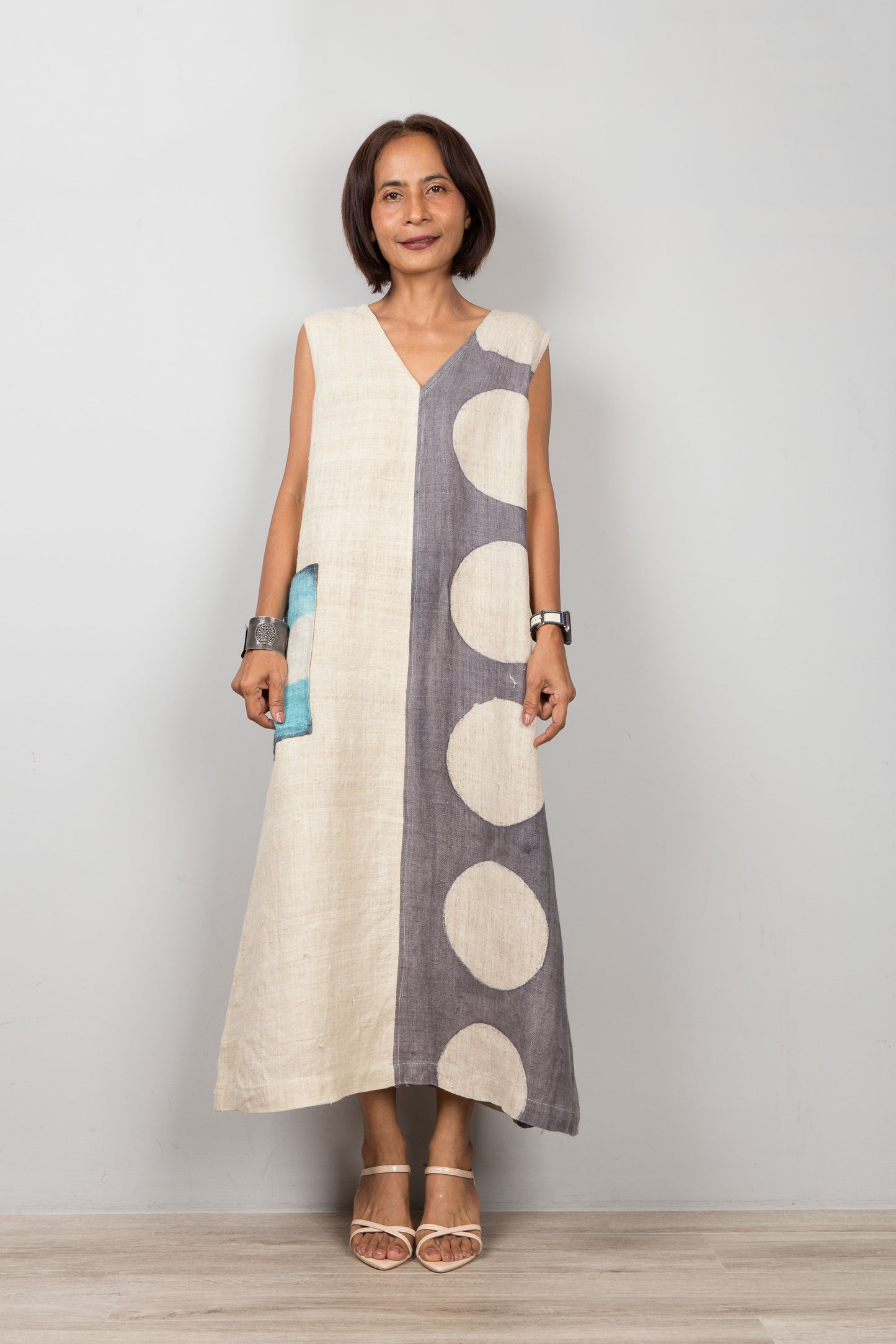 Woman wearing a sleeveless dress with a white and gray pattern on a plain background