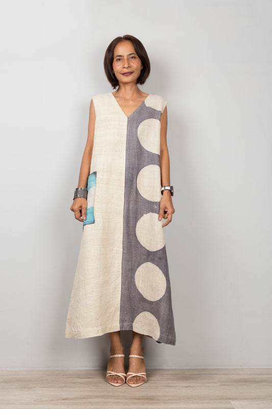 Woman wearing a sleeveless dress with a white and gray pattern on a plain background