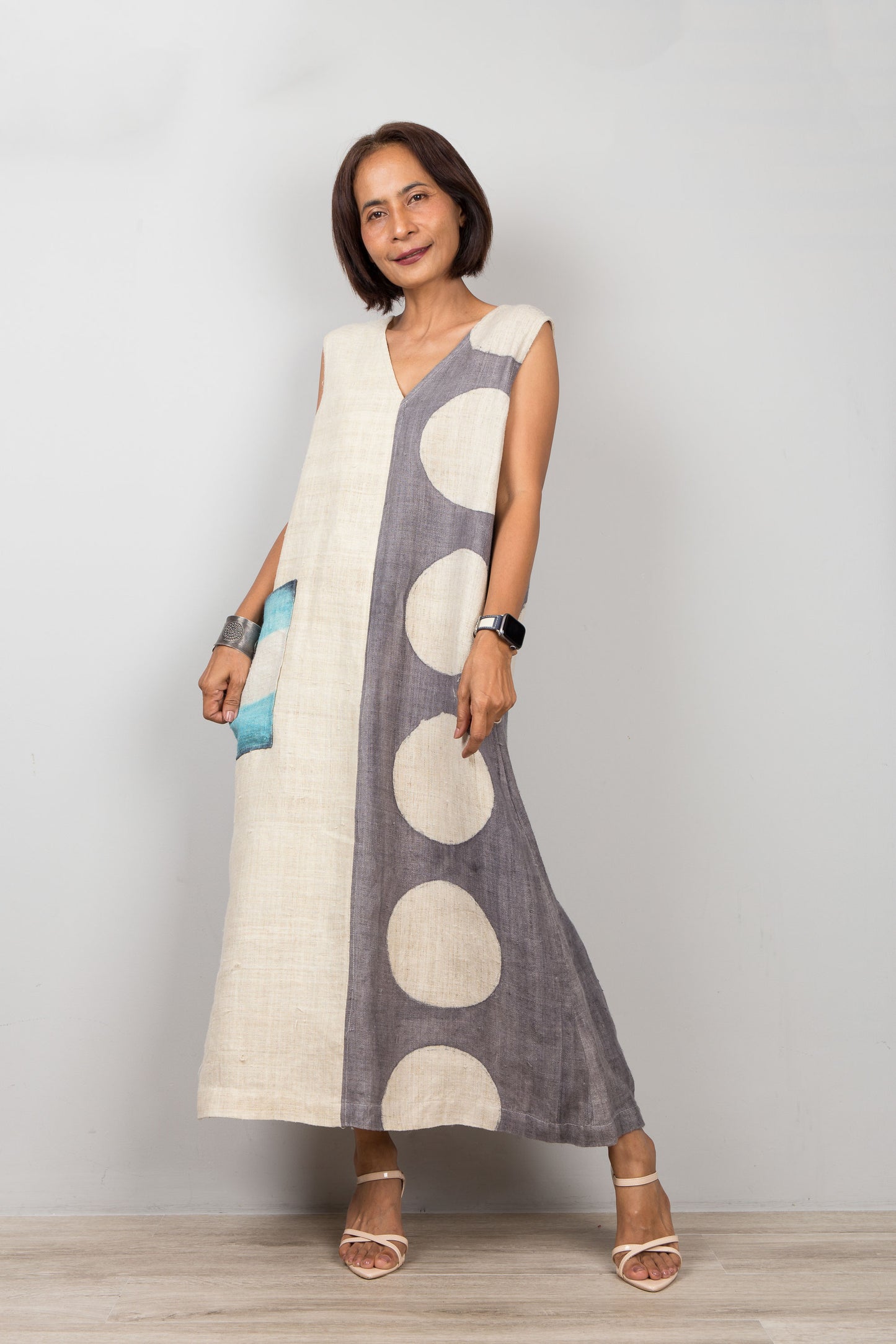 Woman wearing a sleeveless hemp dress with large polka dots on a plain background