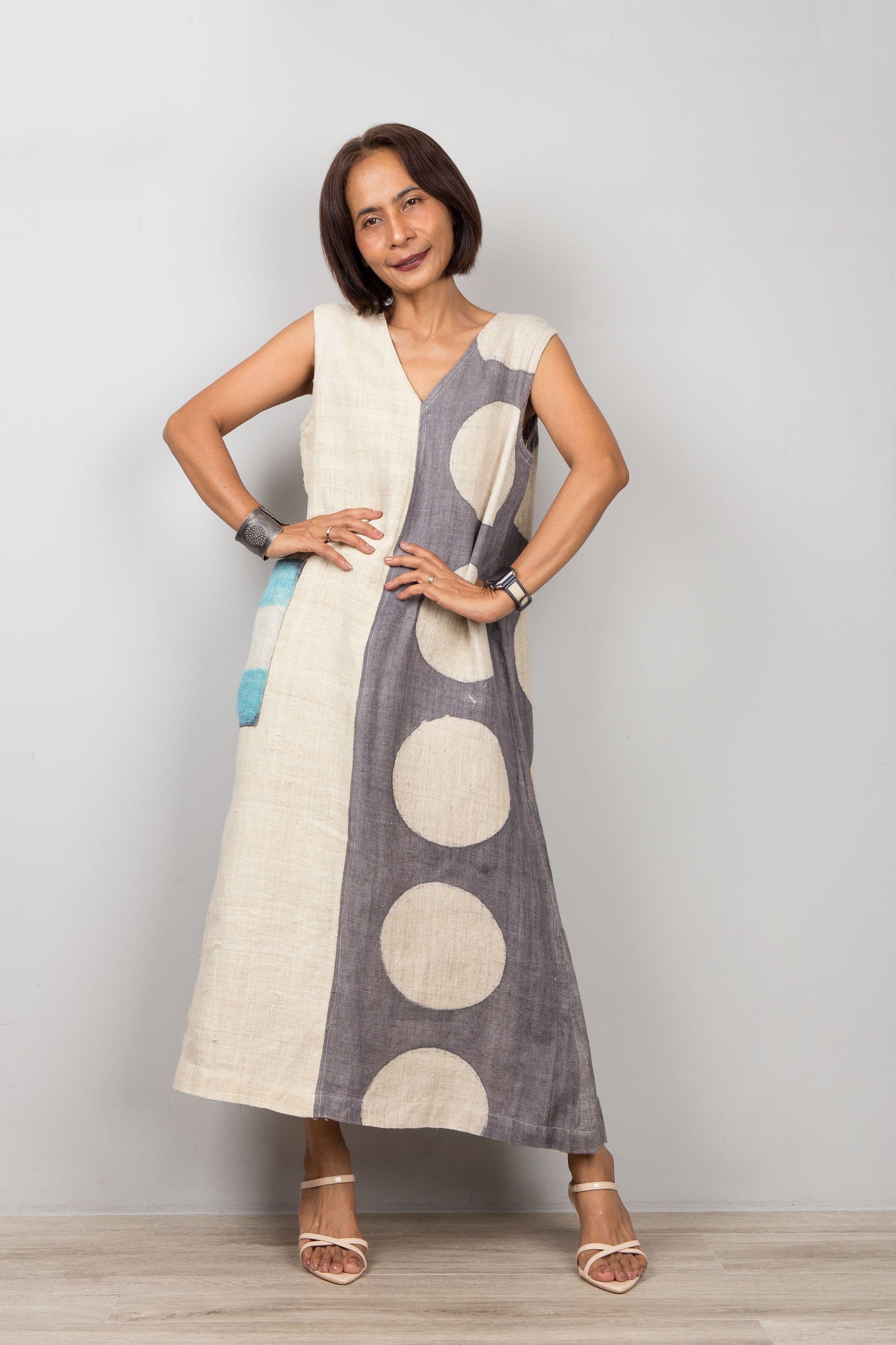 Woman wearing a sleeveless dress with polka dot patterns on a plain background