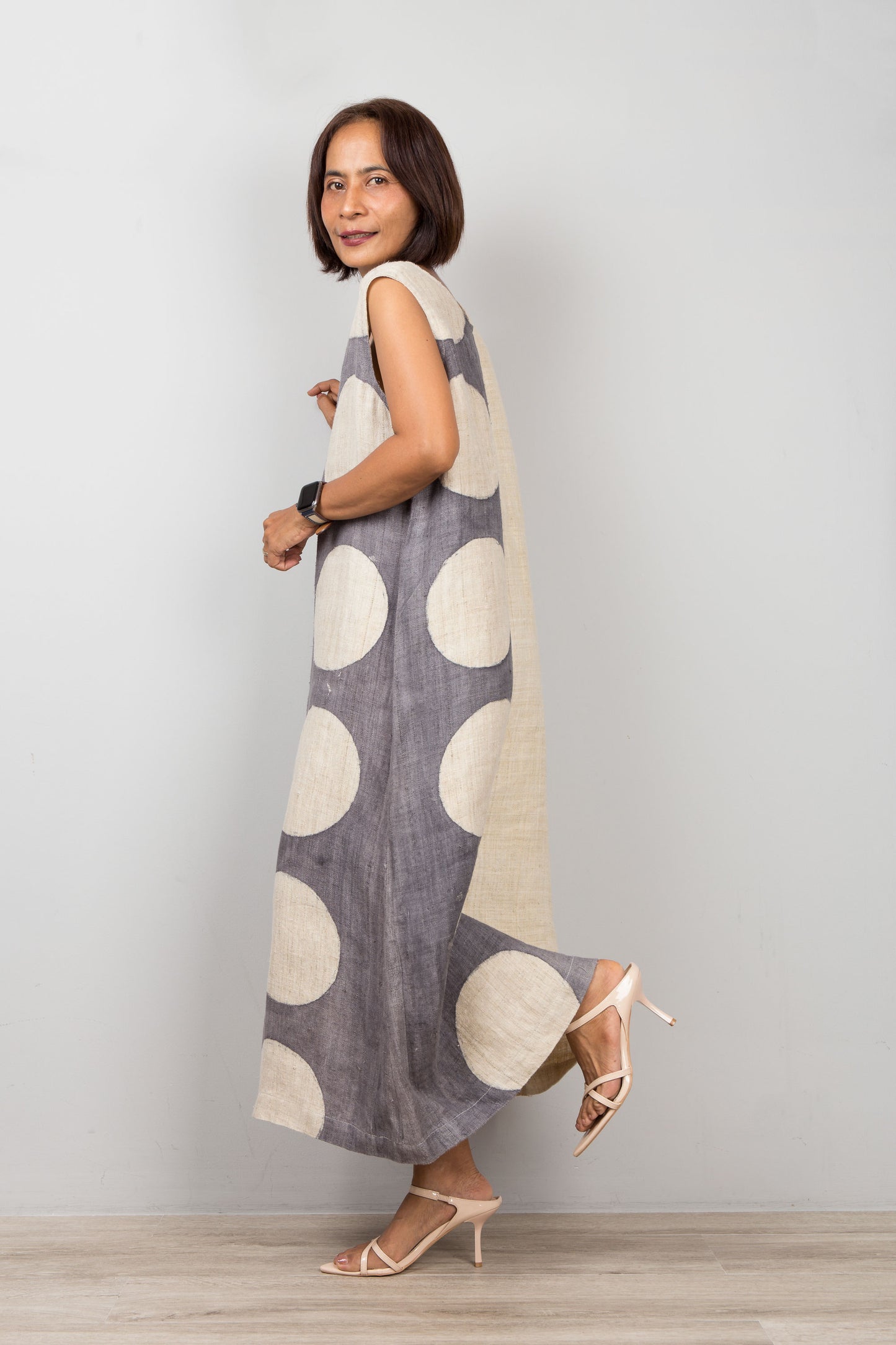 Woman wearing a sleeveless hemp kaftan dress with large circles on a plain background