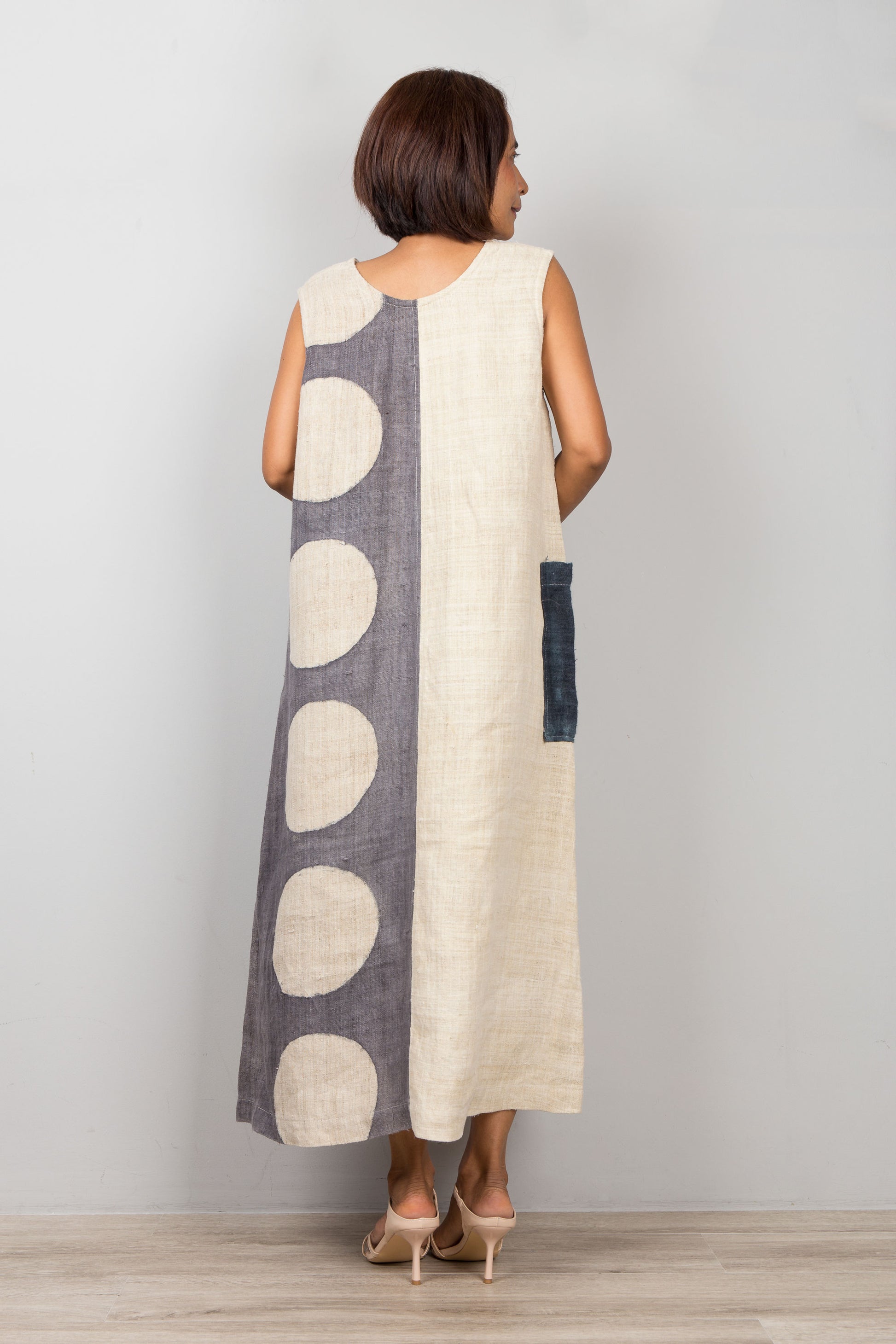 Woman wearing a hemp kaftan dress with circular patterns on a plain background