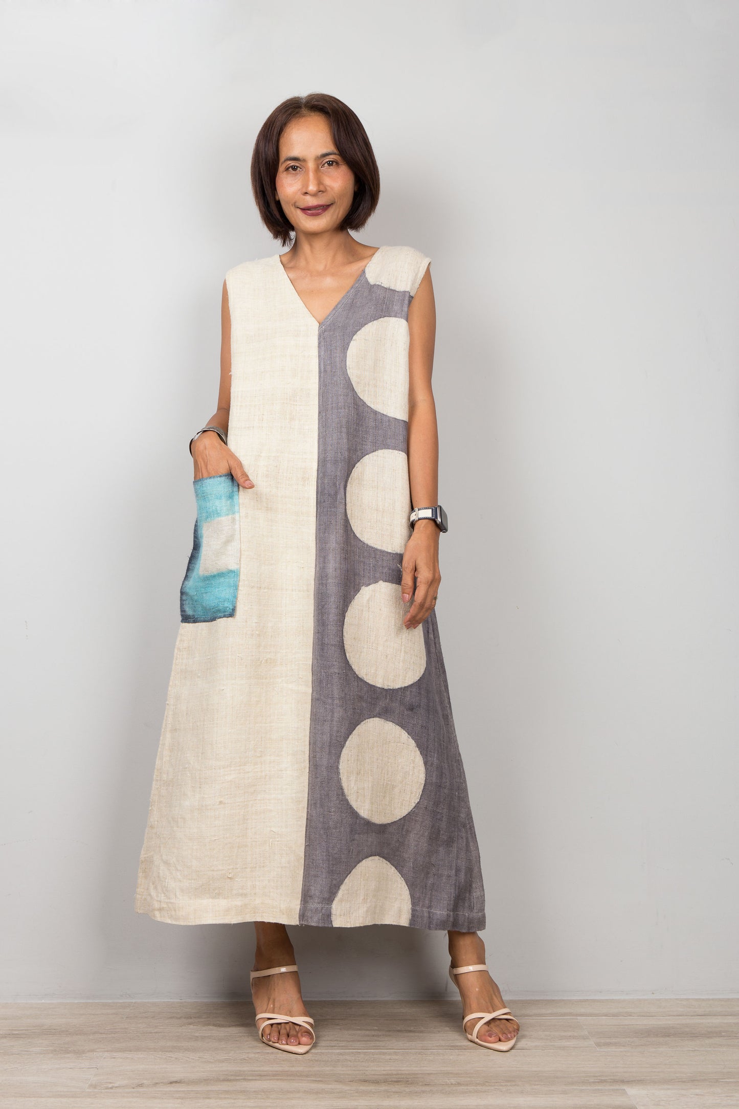 Woman wearing a sleeveless hemp caftan dress with circular patterns on a plain background
