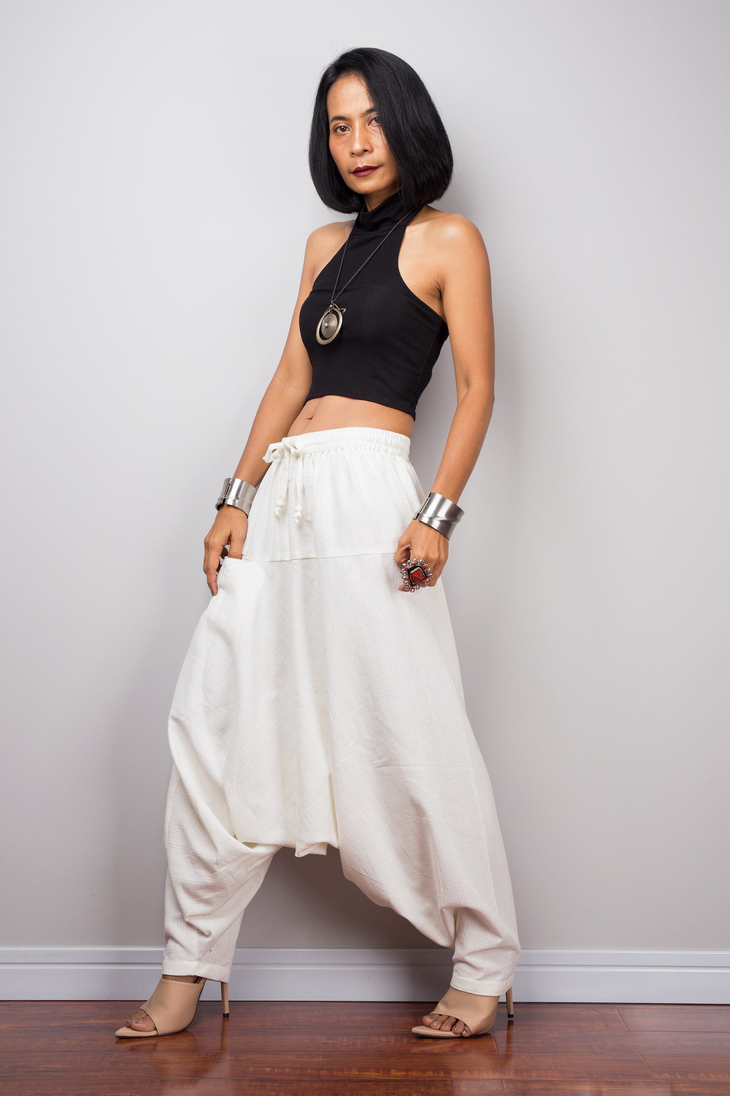 Model wearing white cotton harem pants with a loose fit, standing against a plain background, showcasing the full-length view.