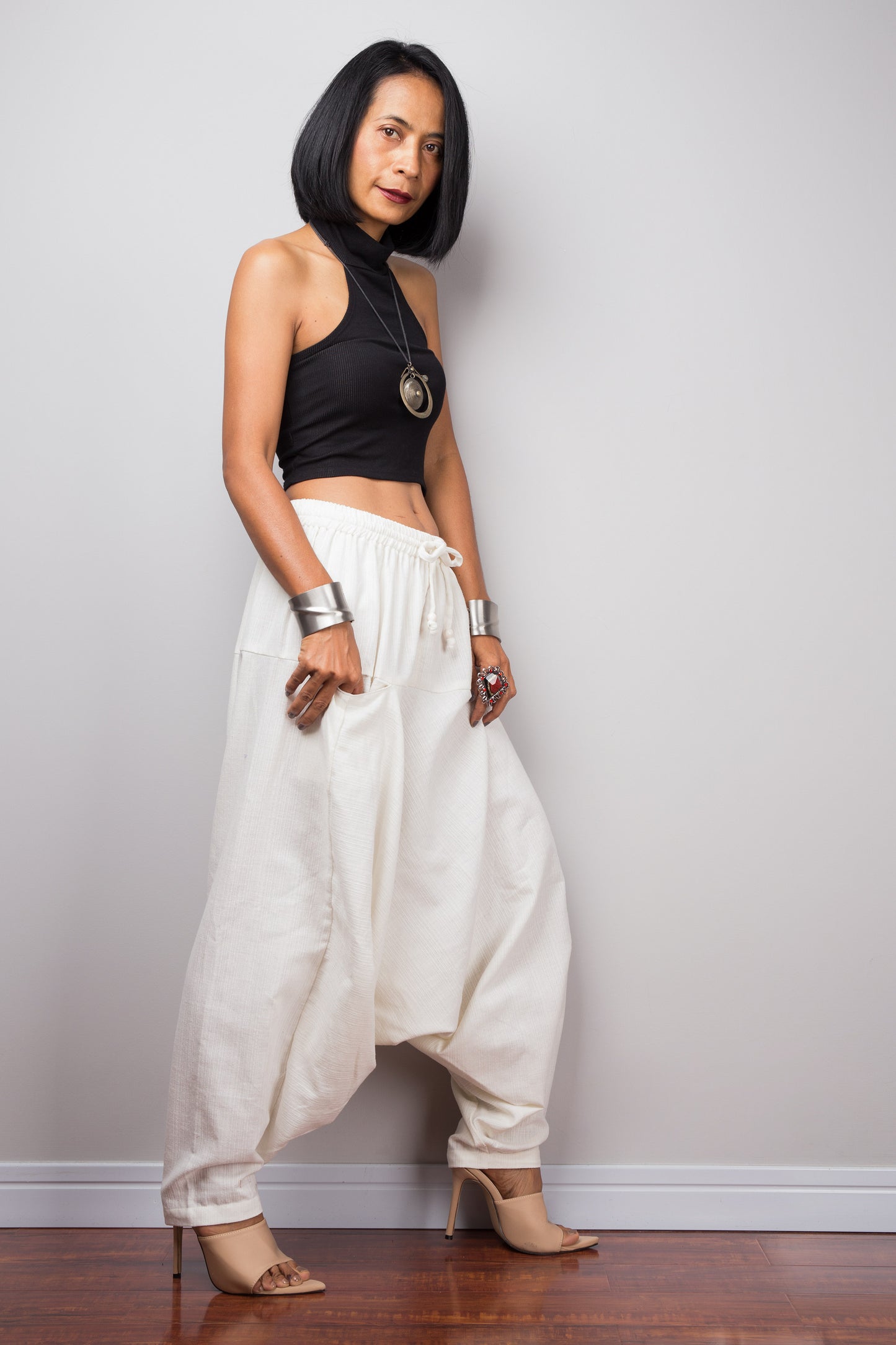 Side view of the white harem pants, displaying the loose fit and the flow of the fabric from the waist to the hem.
