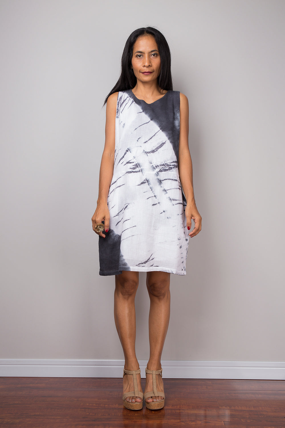 Model wearing a shibori dress with a black and white tie-dye pattern, featuring wave-like designs. This sleeveless boho dress, with its above-knee length is made from soft cotton gauze.

